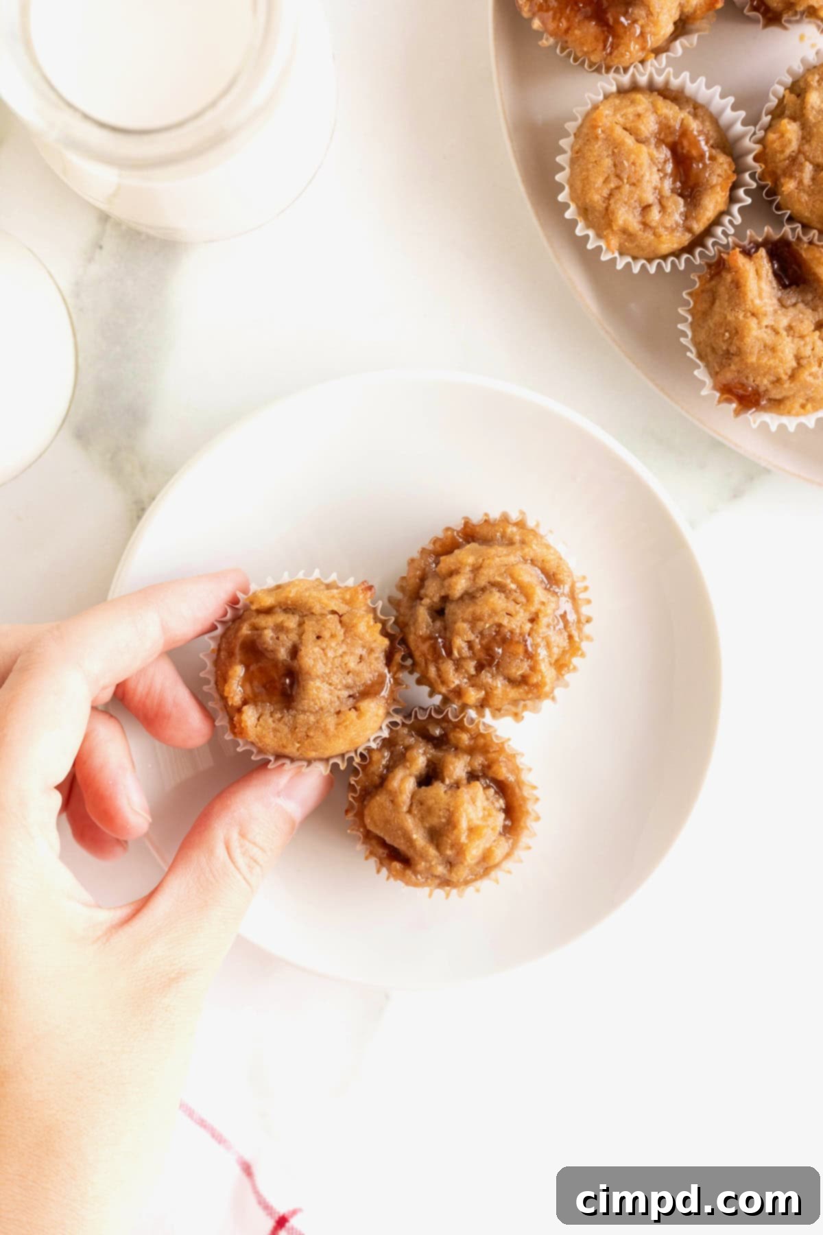 Peanut Butter and Jelly Muffin Bites 4 A small white plate with three peanut butter and jelly mini muffins.