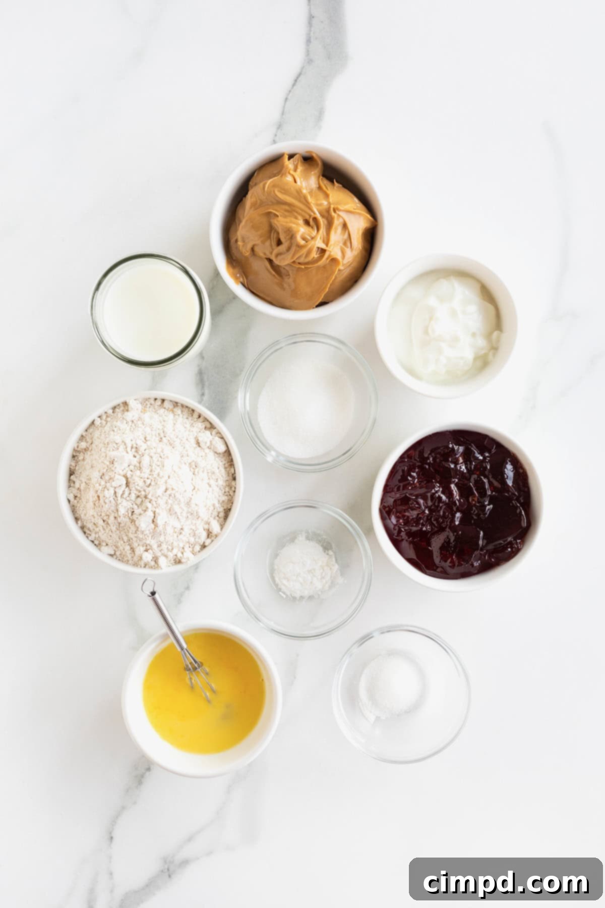 Peanut Butter and Jelly Muffin Bites 5 Ingredients to make peanut butter and jelly muffins in small glass dishes on a white marble counter.