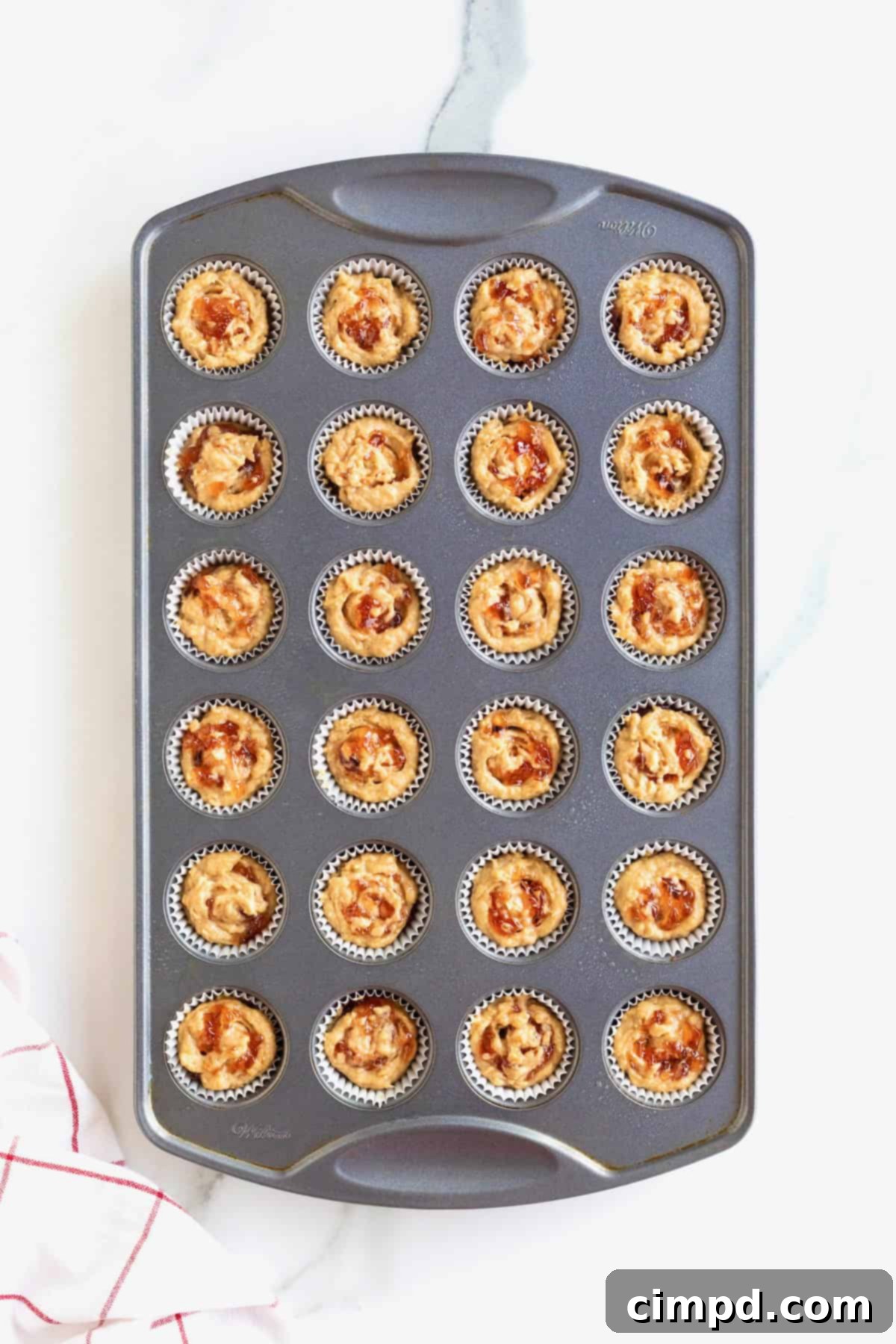 Peanut Butter and Jelly Muffin Bites 8 Peanut butter and jelly muffin batter in a dark muffin pan.