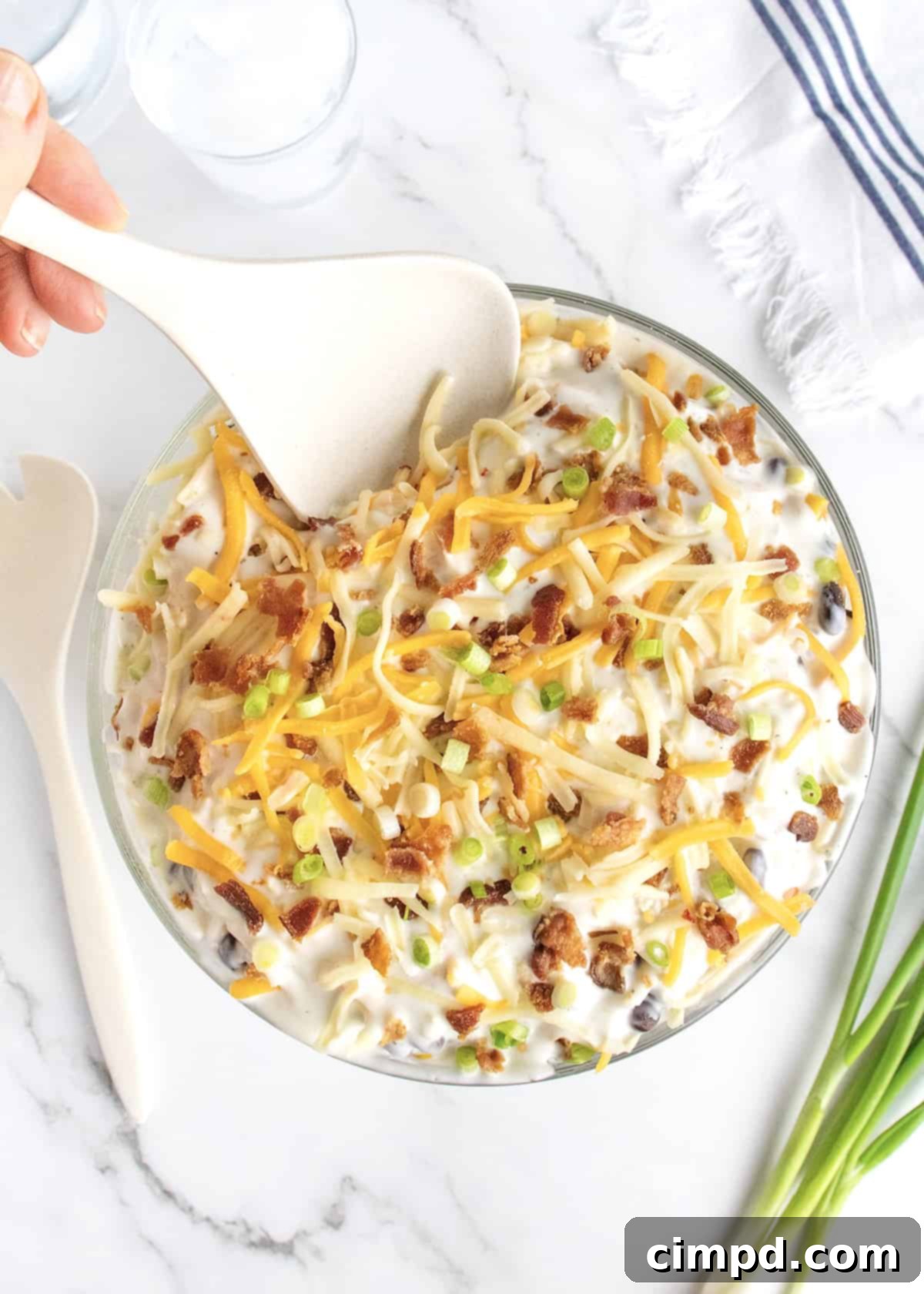 Southern Stacked Cornbread Medley 4 Layered Cornbread Salad showcased in a clear glass serving dish with a white serving spoon.