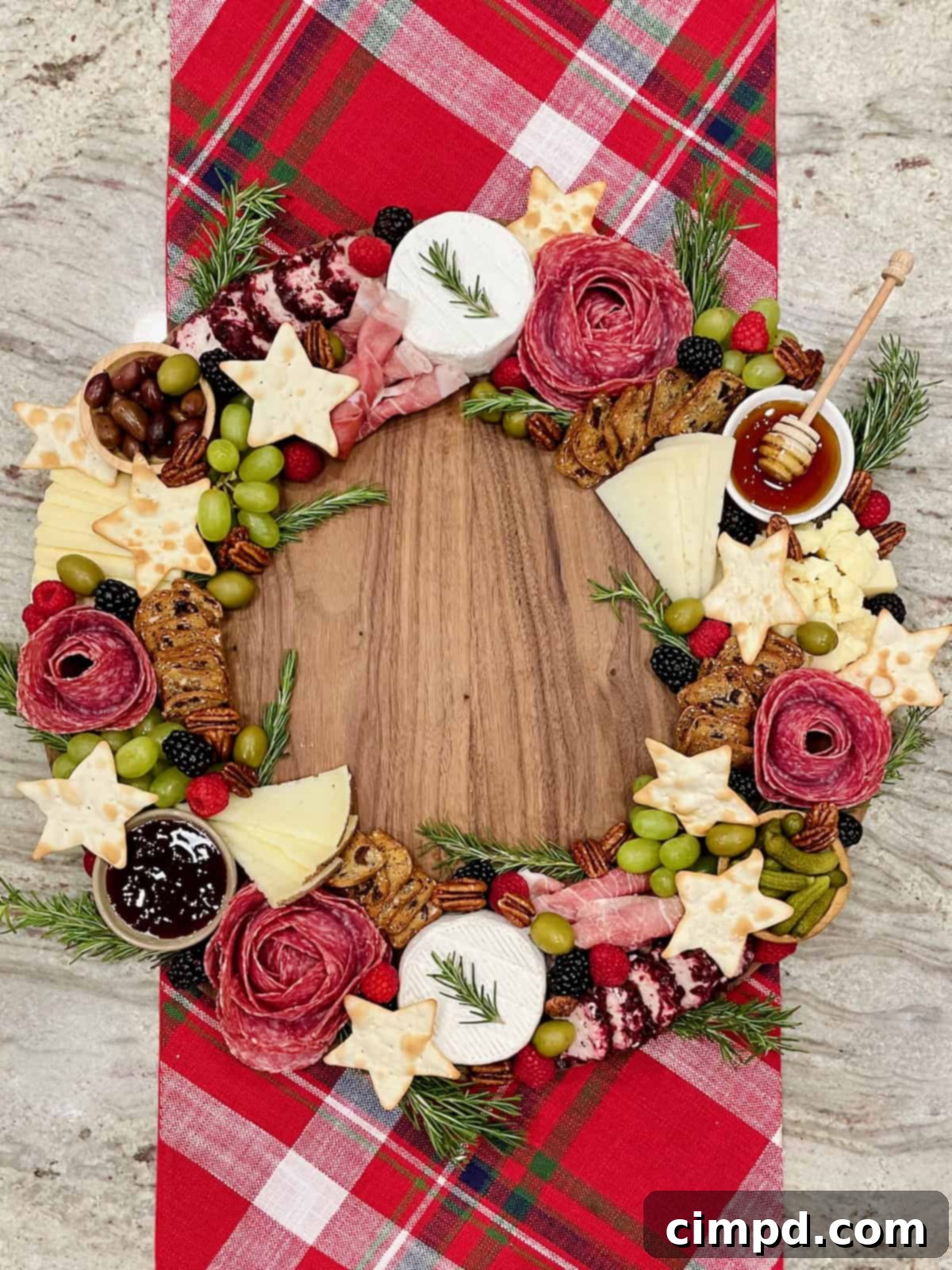 A festive charcuterie board expertly arranged to resemble a holiday wreath, adorned with cheeses, meats, fruits, and crackers.