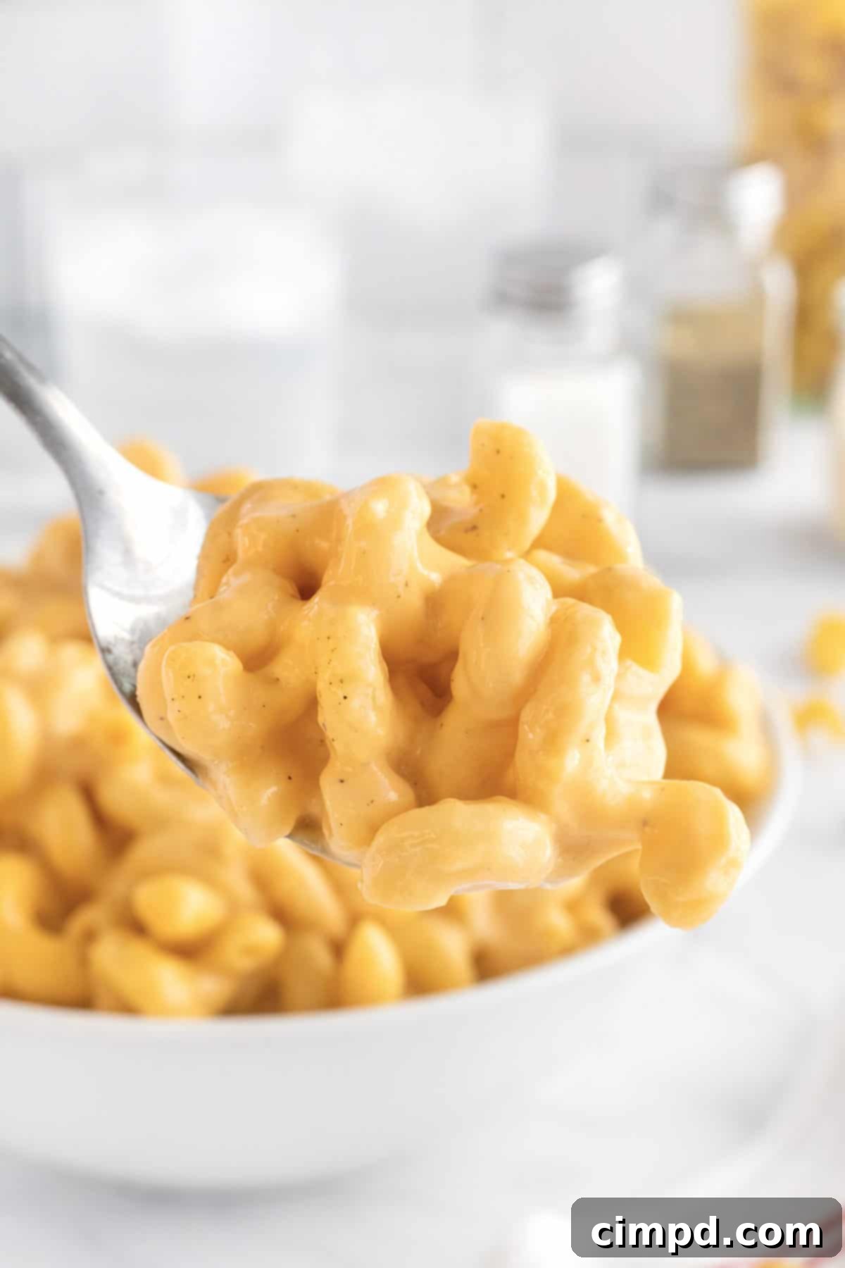 Close-up shot of stovetop macaroni and cheese with a focus on its creamy texture and golden hue.