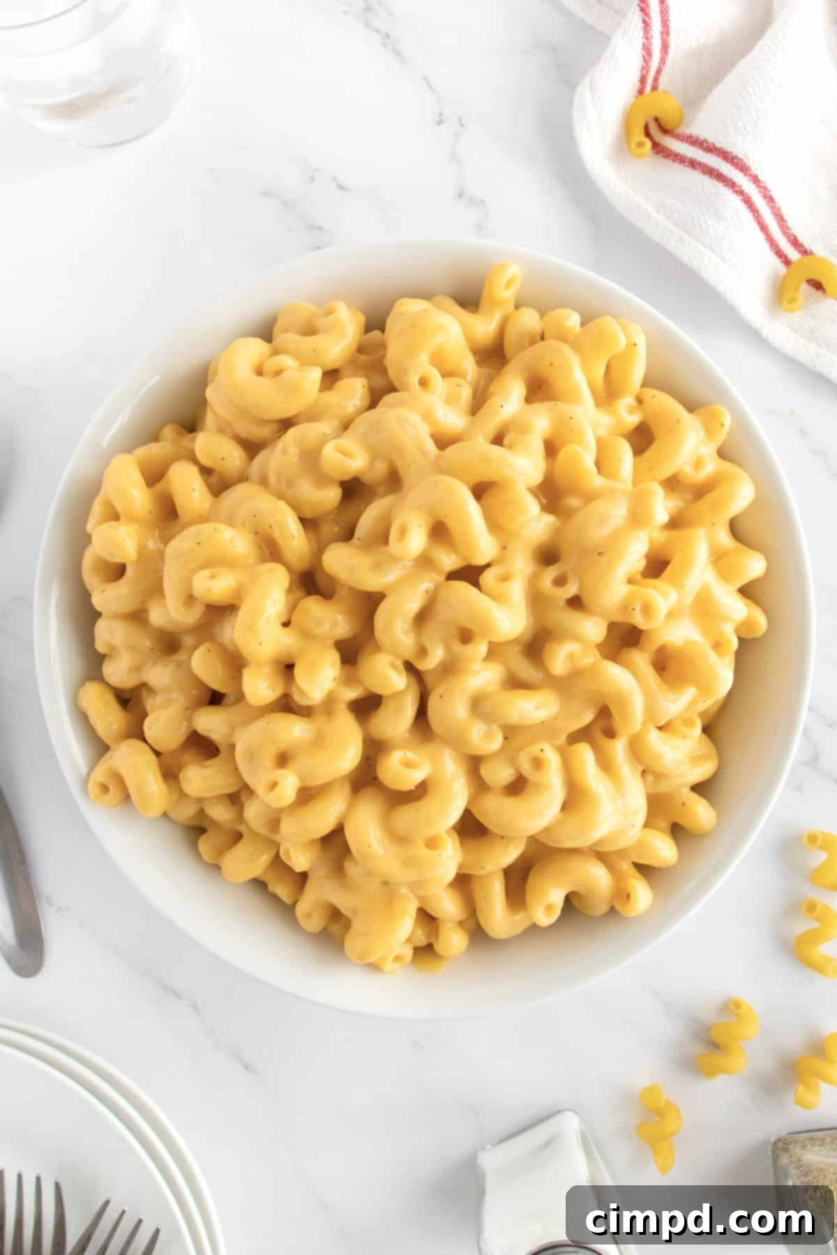 A large white serving bowl overflowing with golden, creamy macaroni and cheese, ready to be enjoyed.