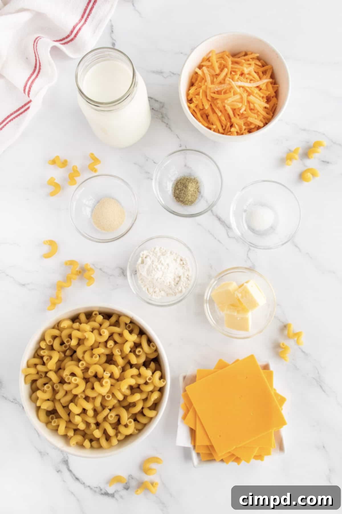 The BakerMama's Stovetop Macaroni and Cheese ingredients laid out, showcasing the pasta, cheeses, and liquids.