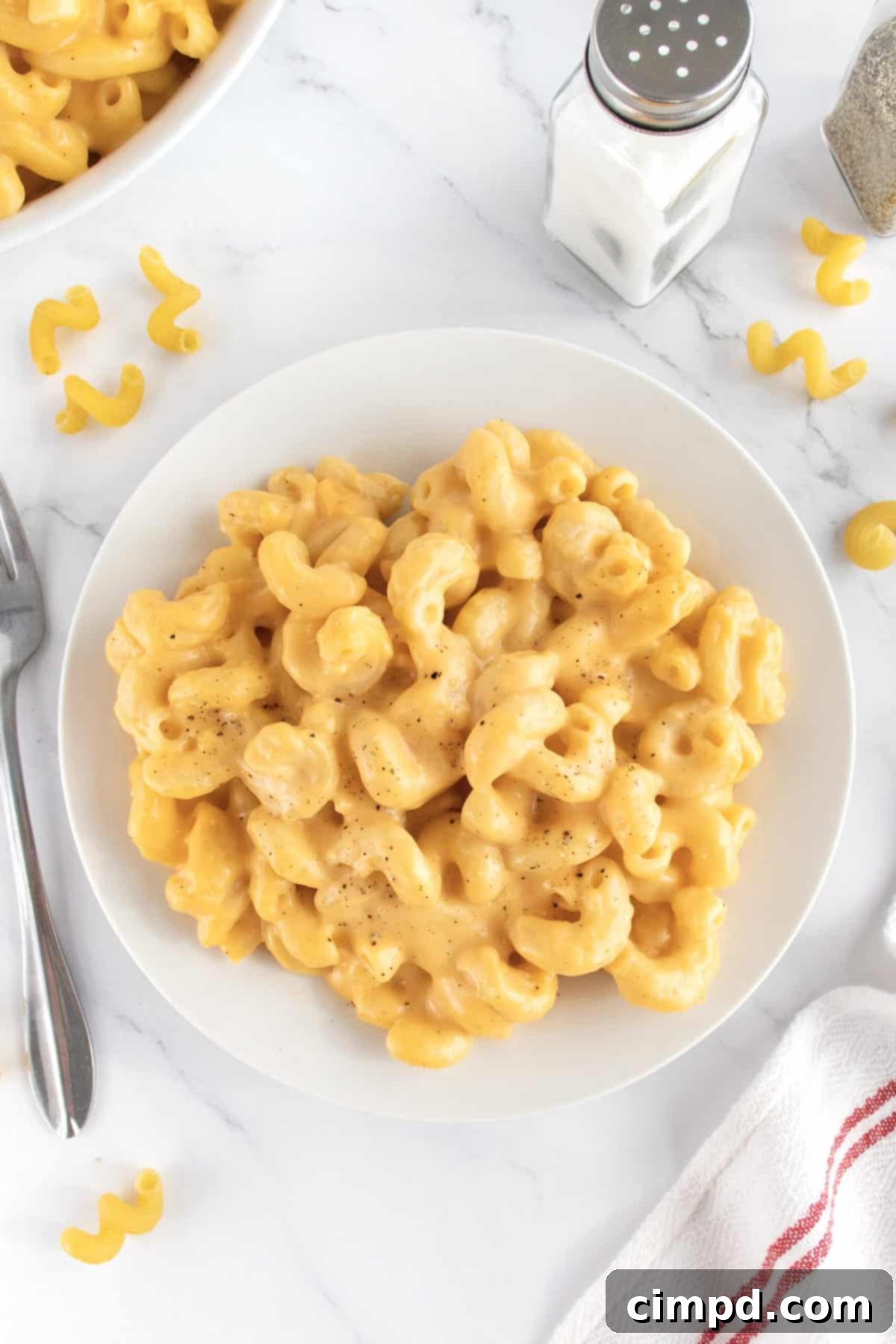 A close-up of a serving of Stovetop Macaroni and Cheese in a white bowl, garnished with a sprinkle of fresh parsley.