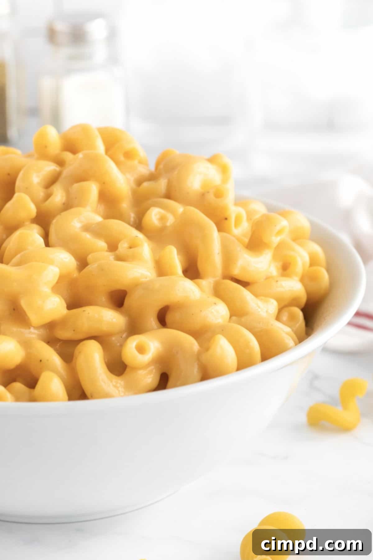 A large white bowl filled with golden, creamy macaroni and cheese, ready for serving or storing.