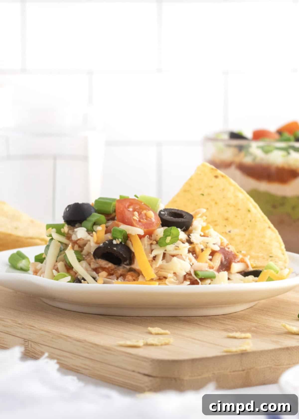 Another appealing shot of the 7-Layer Dip, highlighting its vibrant layers and fresh garnishes, ready to be served at a festive occasion.