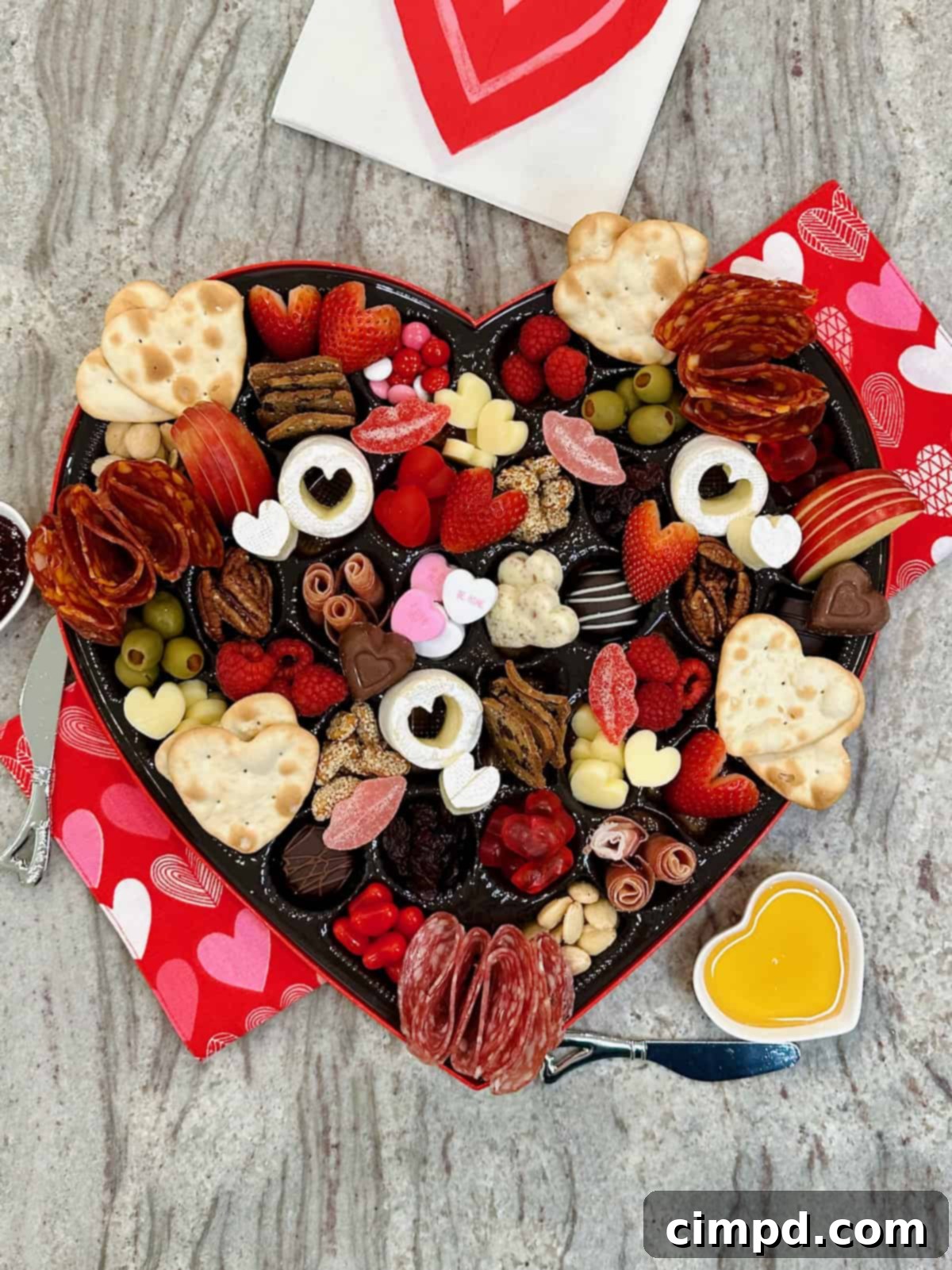 Close-up of heart-shaped charcuterie board with detailed ingredients.