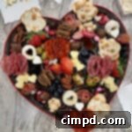 Heart shaped chocolate candy box filled with cheeses, meats, crackers, fruits, nuts and candies.
