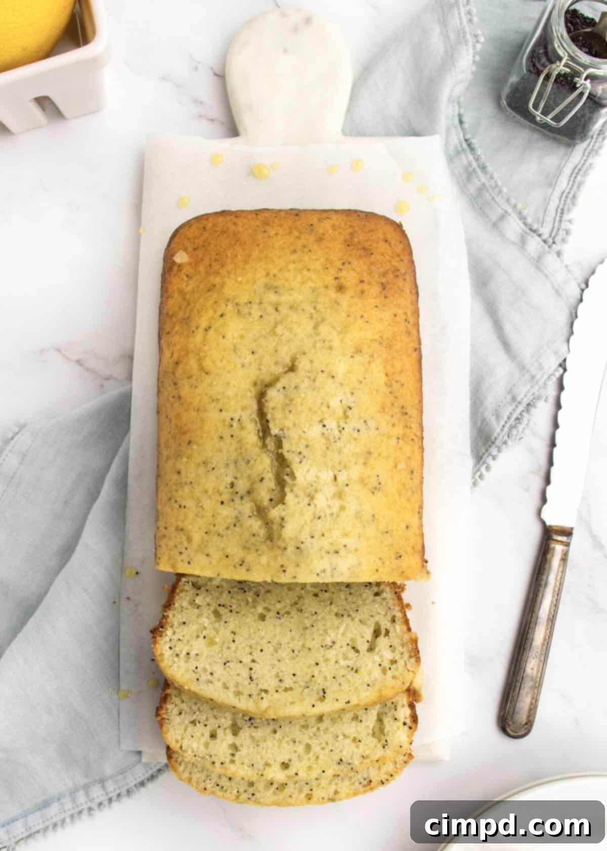 Freshly baked Lemon Poppy Seed Bread, glistening with glaze, by The BakerMama