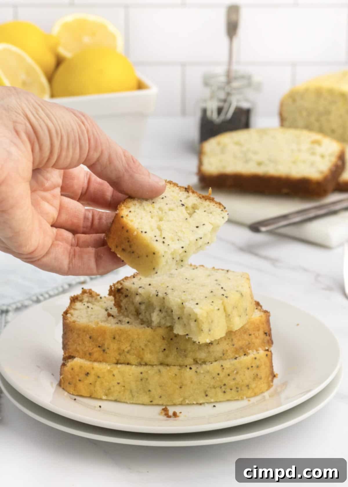 Close-up of a slice of Lemon Poppy Seed Bread, showing its moist texture and poppy seeds, by The BakerMama