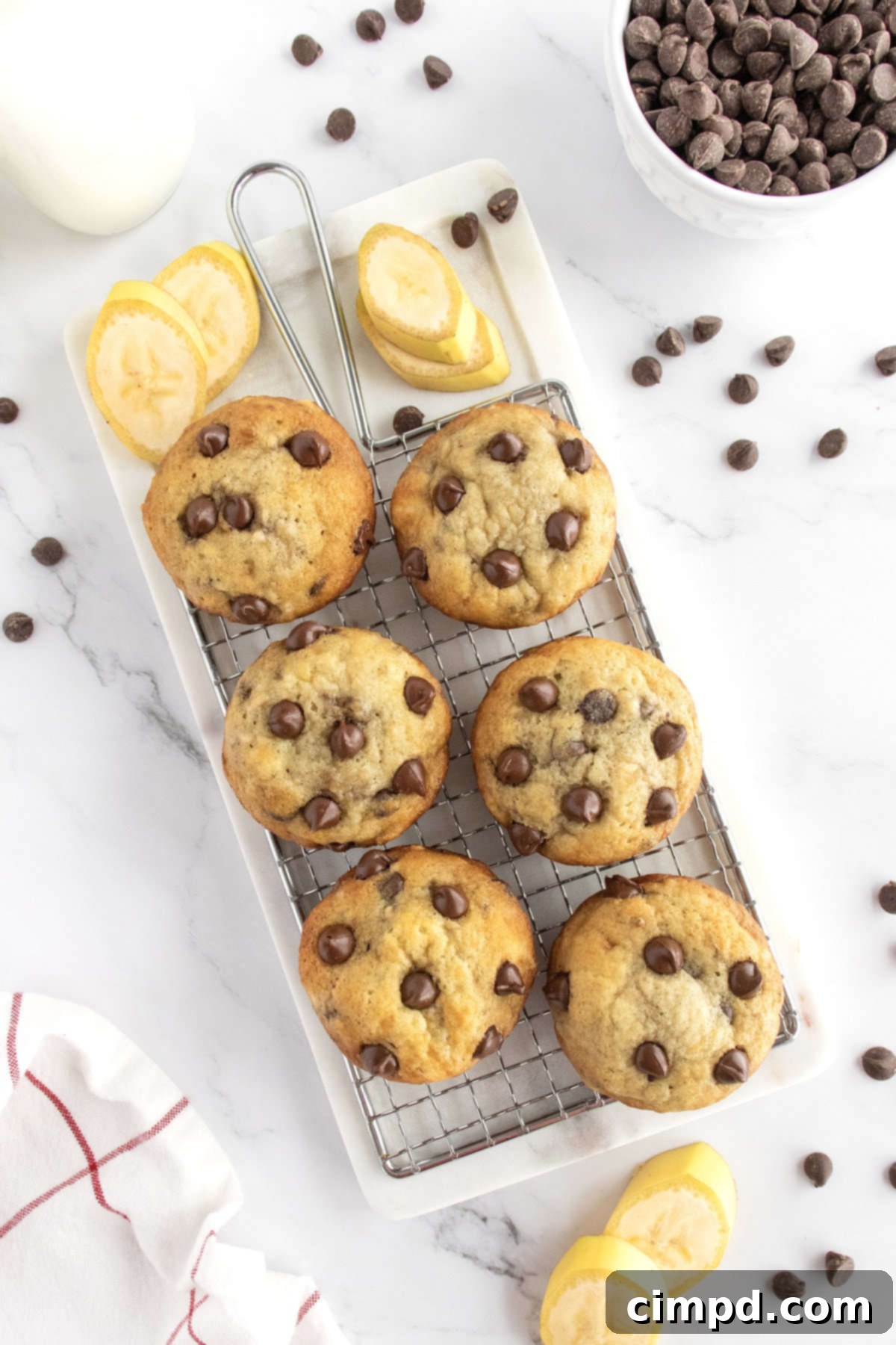 Six banana chocolate chip muffins on a wire rack. 