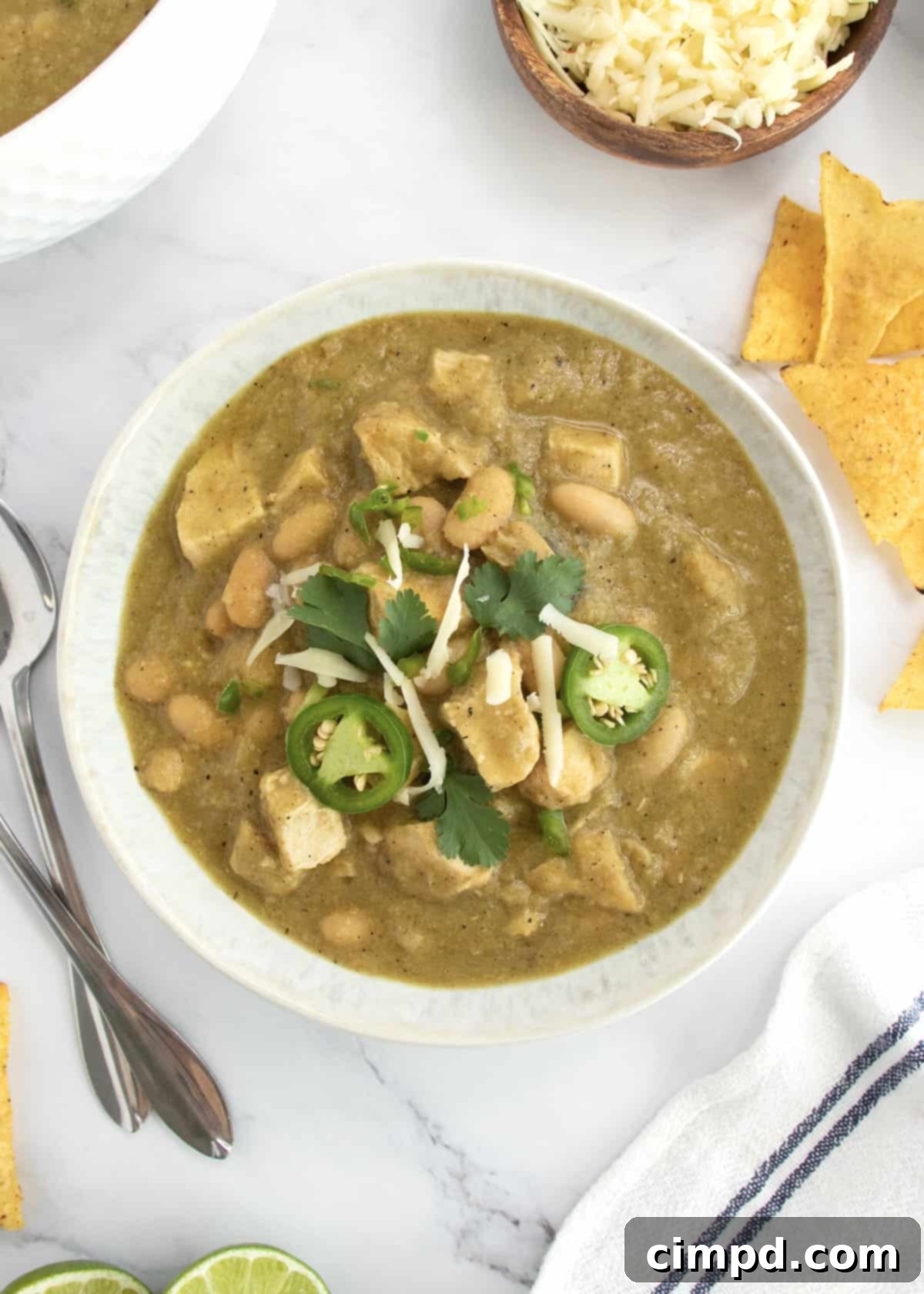 Zesty Green Chicken Chili 4 Close-up of Green Chicken Chili in a rustic bowl, garnished with cheese and cilantro.
