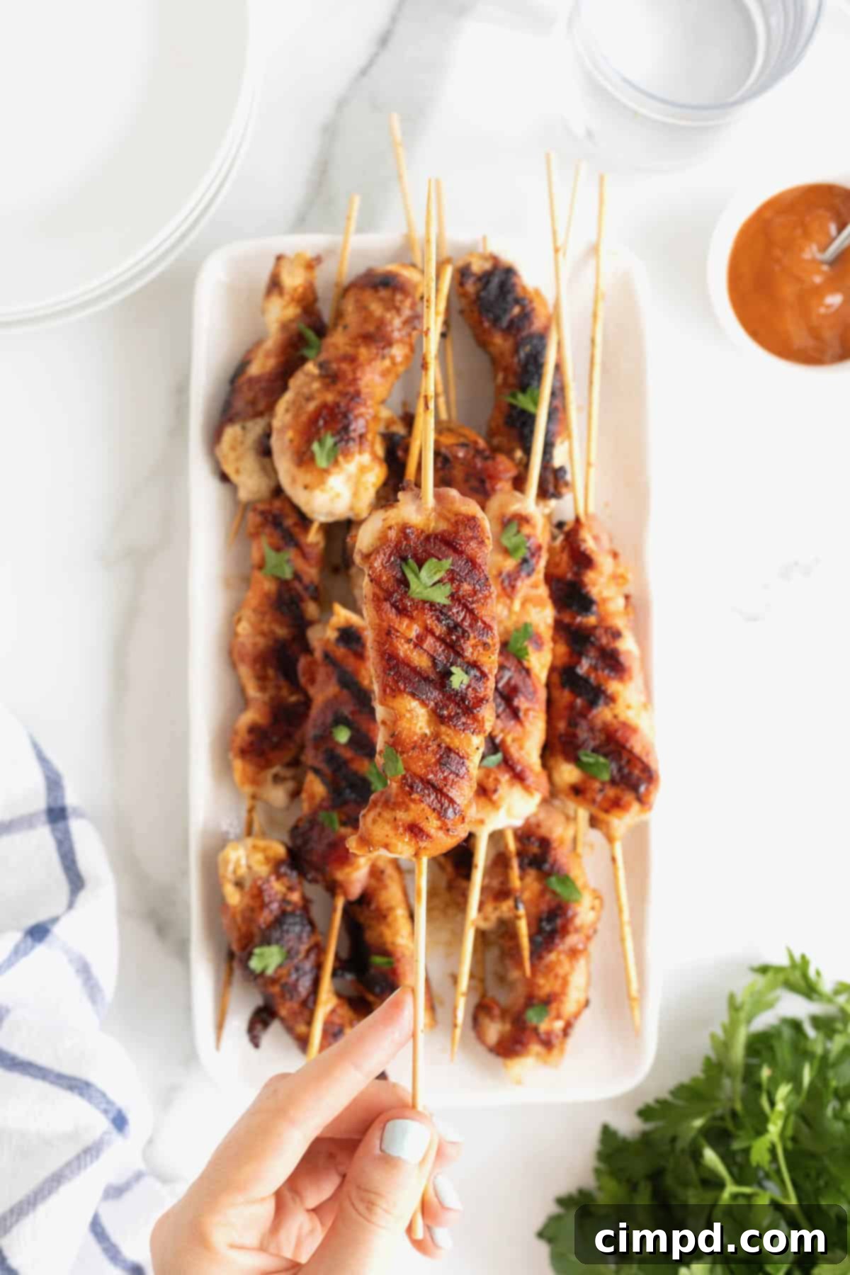 Crispy Bacon Chicken Skewers 6 A rectangular white serving platter displaying an abundant pile of grilled chicken skewers.