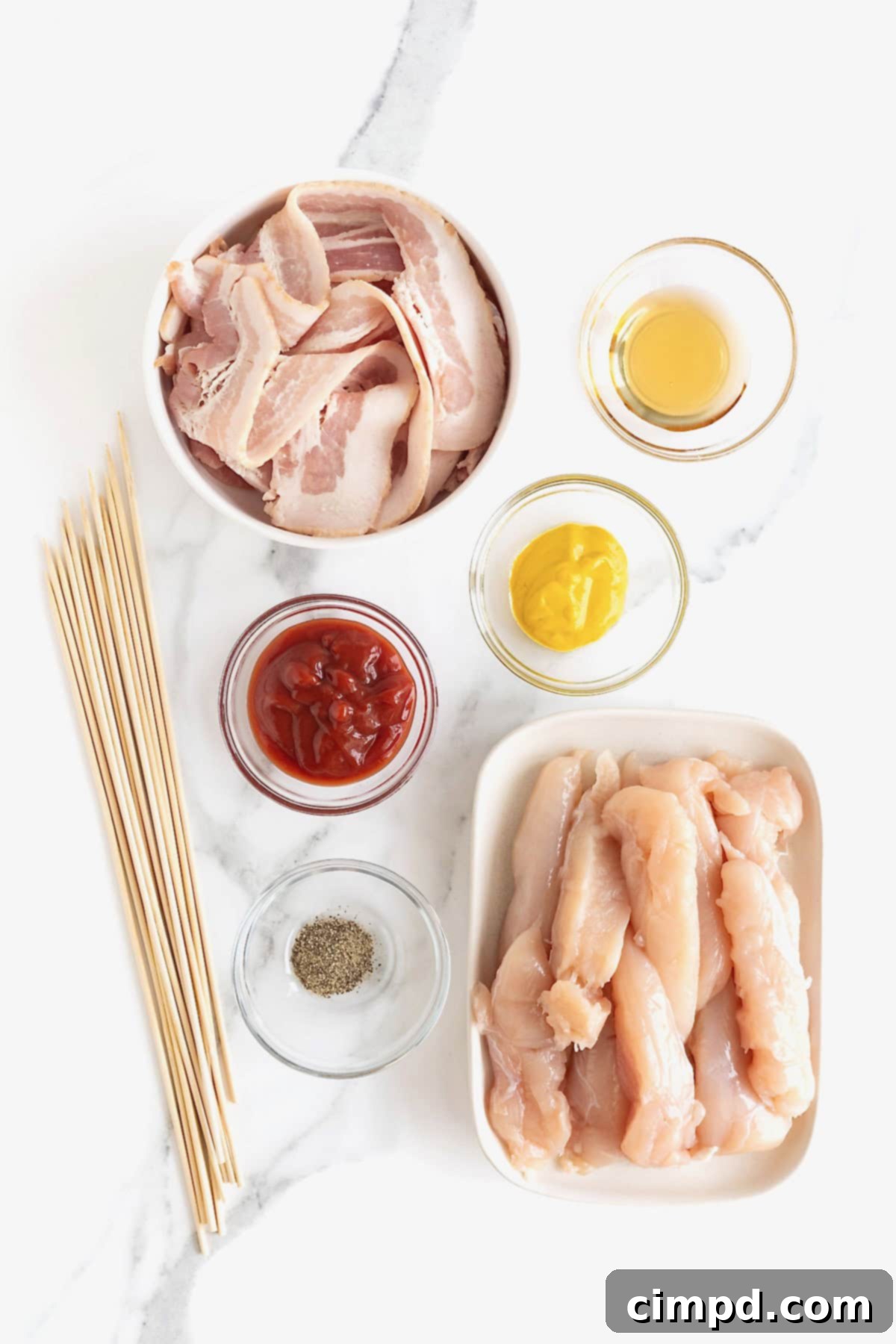 Crispy Bacon Chicken Skewers 7 Various ingredients laid out for making grilled chicken skewers wrapped in bacon, including chicken tenderloins, bacon, ketchup, mustard, maple syrup, and black pepper.