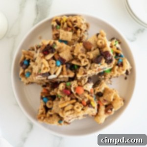 No-Bake Grab-and-Go Bars 11 Snack bars made with cereal, pretzel sticks and M&M's on a white plate.