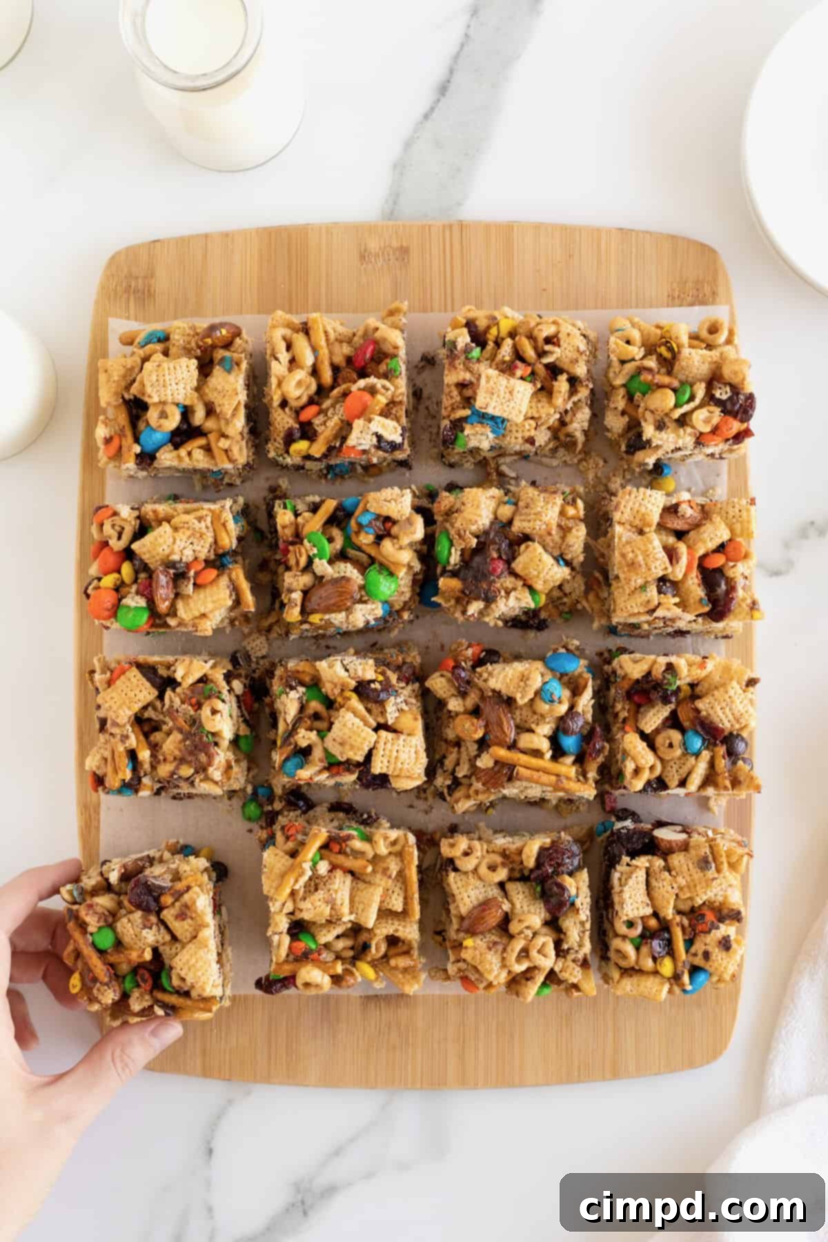 No-Bake Grab-and-Go Bars 4 Multiple delicious no-bake snack bars, featuring a mix of cereal, pretzel pieces, and M&M's, arranged neatly on a rustic wooden cutting board.
