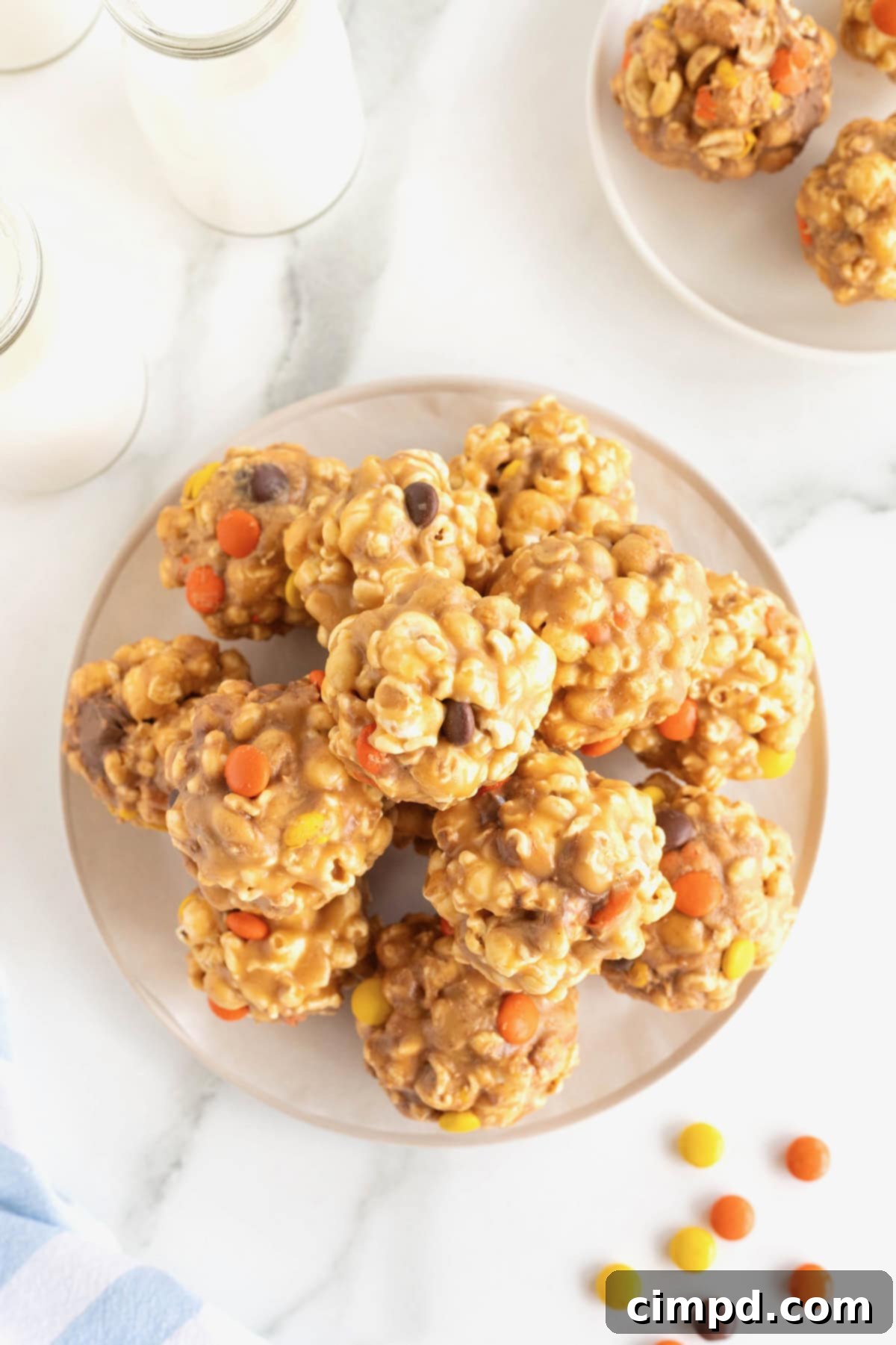 A round serving plate piled with loaded popcorn peanut butter balls on a white marble counter.