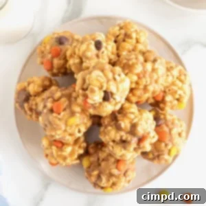 A white round serving plate piled with loaded popcorn peanut butter balls on a white marble counter.