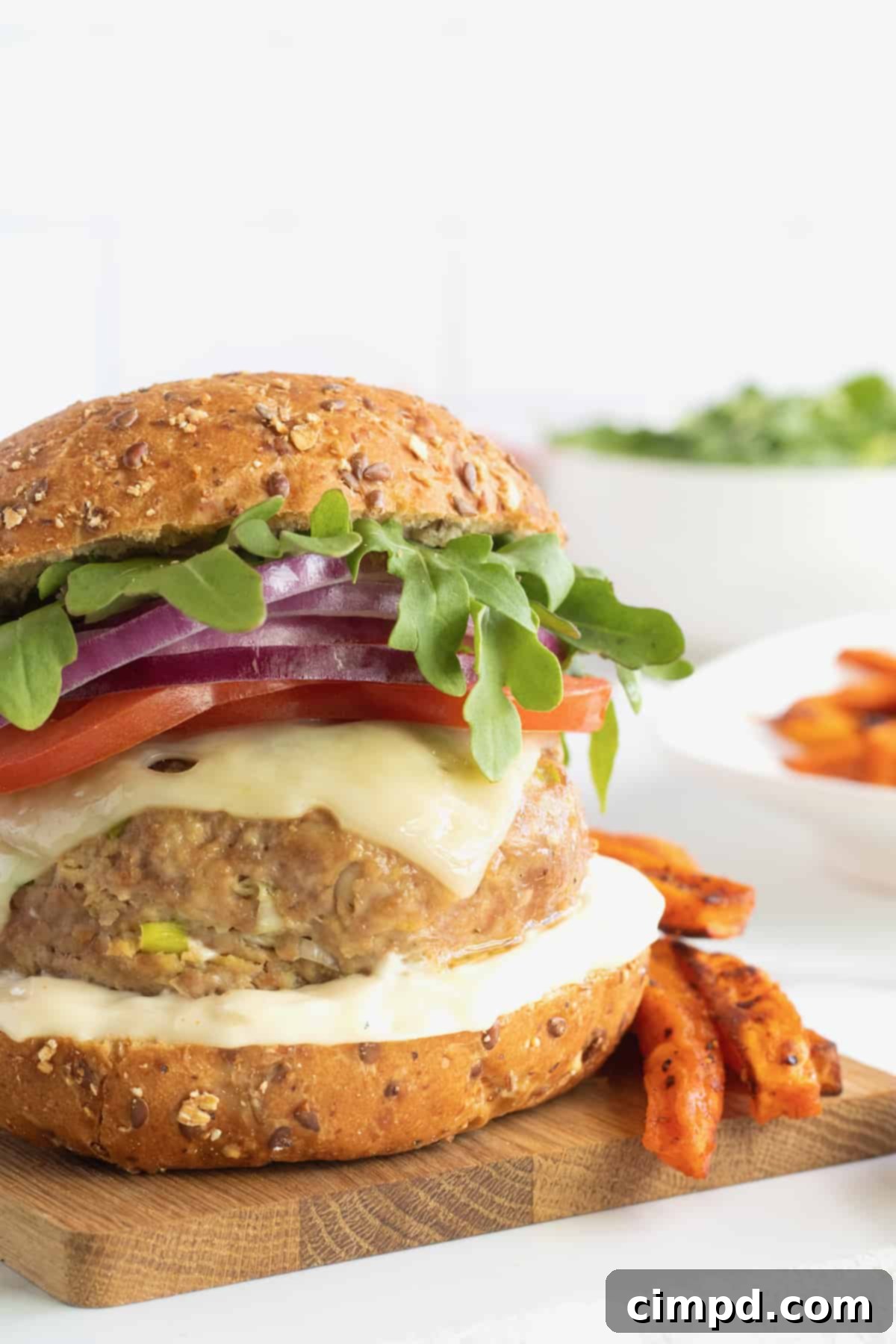Fire-Kissed Turkey Burgers 6 A fully assembled turkey burger with melted cheese, arugula, and red onion, served with sweet potato fries.