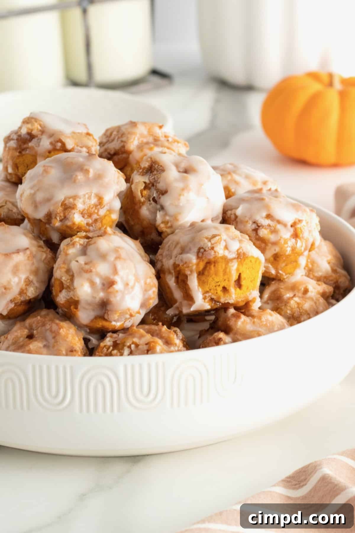 Baked Pumpkin Poppers 2 Close-up of golden-brown baked pumpkin fritter bites drizzled with a sweet glaze, ready to be enjoyed.