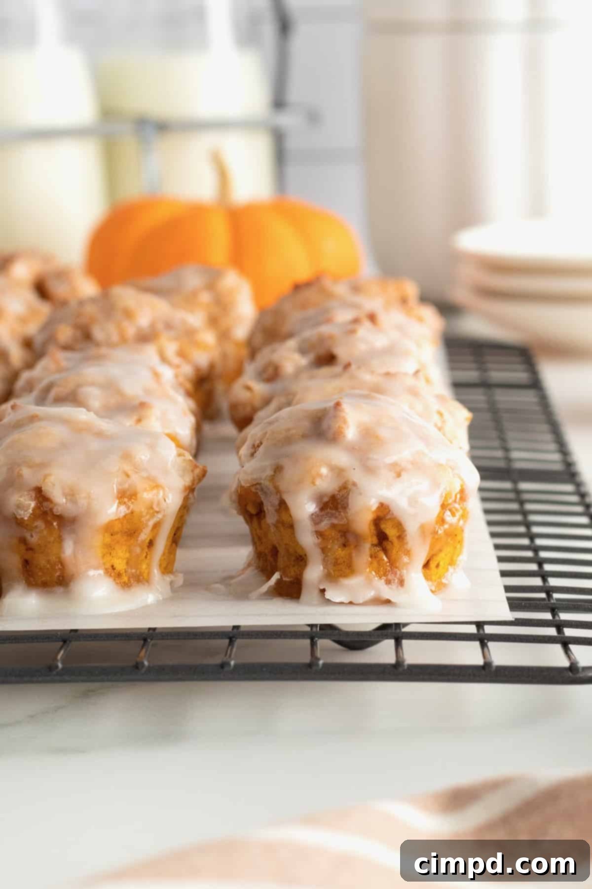 Baked Pumpkin Poppers 10 A close-up of a single glazed baked pumpkin fritter bite, perfectly golden and appetizing.