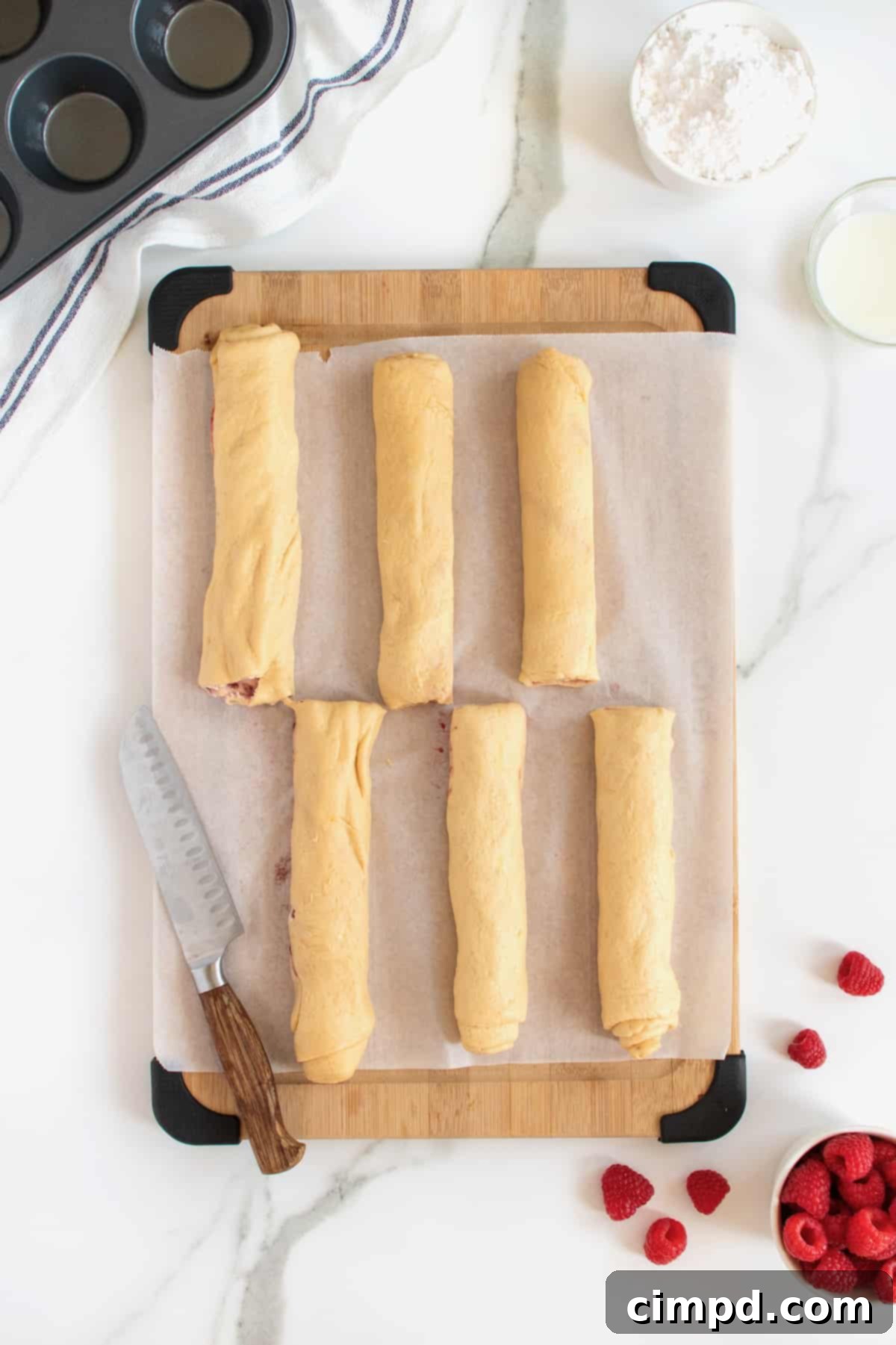The step demonstrating how to cut the rolled dough logs in half, creating shorter segments for easier handling.