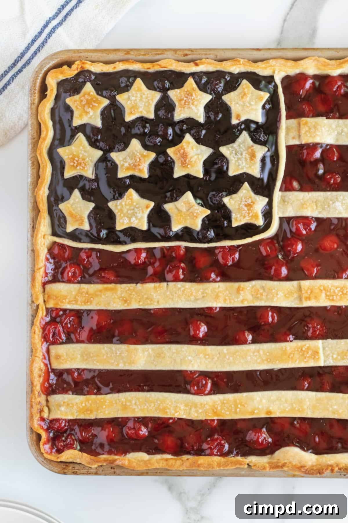 Stars and Stripes Pie 3 Close-up of a slice of American Flag Pie on a white plate, showing the distinct cherry and blueberry fillings and the golden crust.