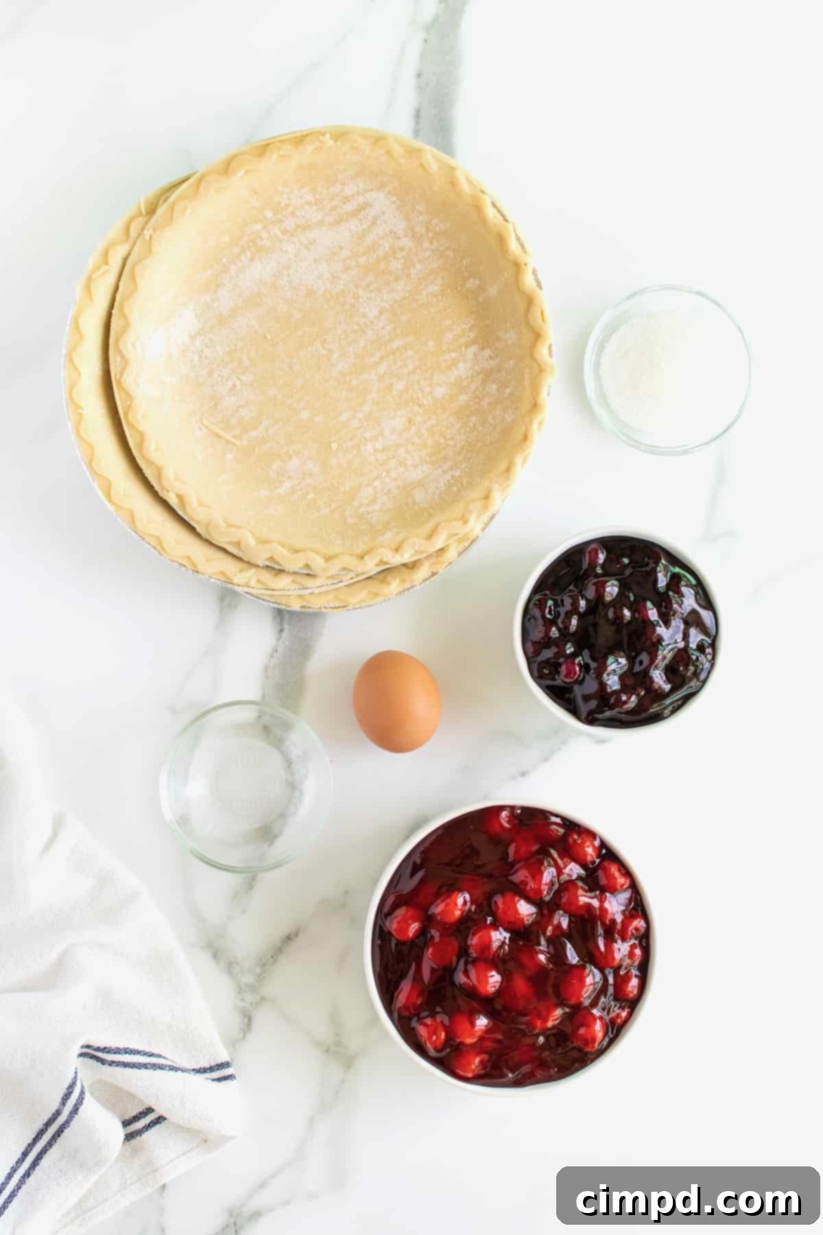 Stars and Stripes Pie 5 Gathered ingredients for American Flag Pie including pie crusts, cherry and blueberry fillings, egg, water, and sparkling sugar.