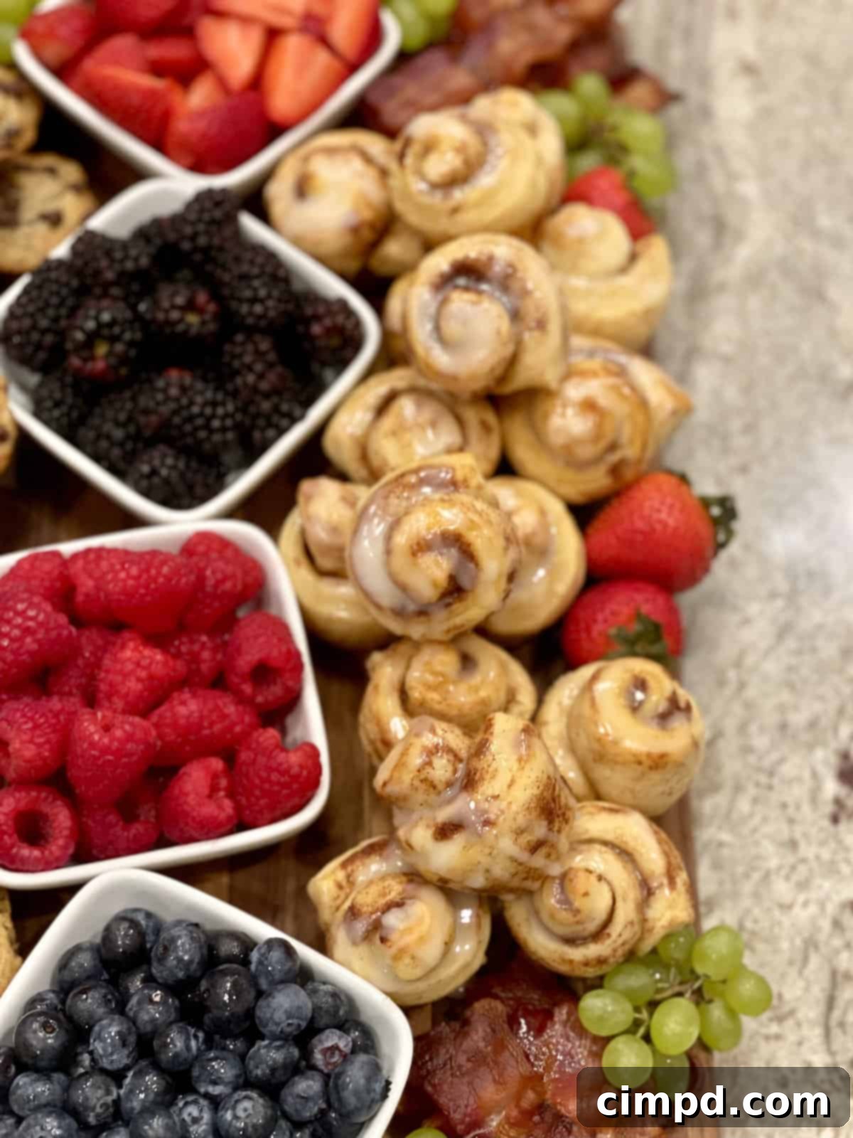 A close-up shot of freshly baked Mini Cinnamon Rolls, glistening with white icing, arranged in a mini muffin pan.