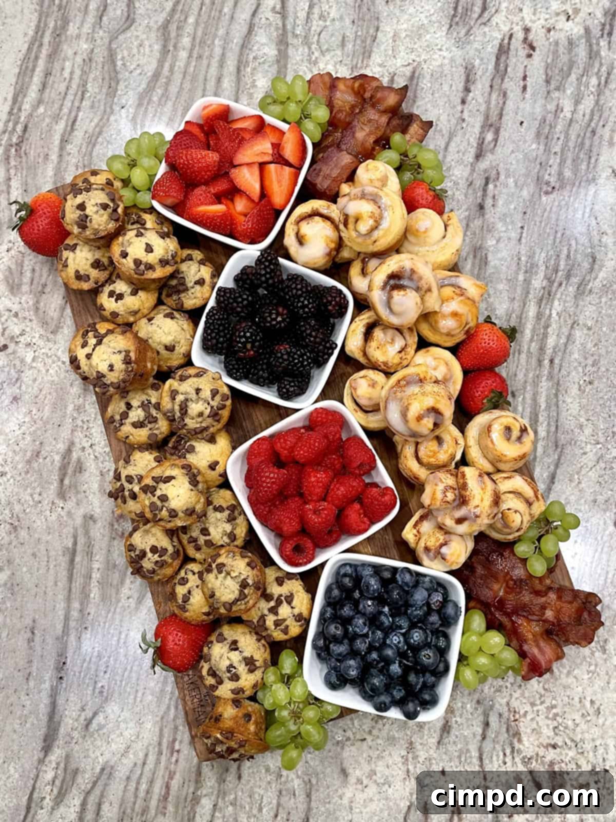 An overhead view of a fully assembled Mini Muffin and Cinnamon Roll Breakfast Board, bursting with color and texture, showcasing all the delicious components ready to be enjoyed.