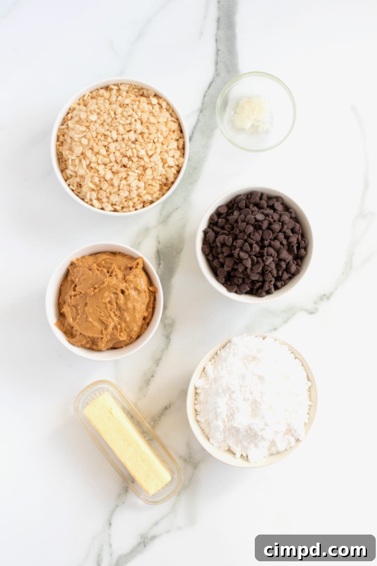 Ingredients for chocolate covered peanut butter balls in small glass dishes on a white marble counter.