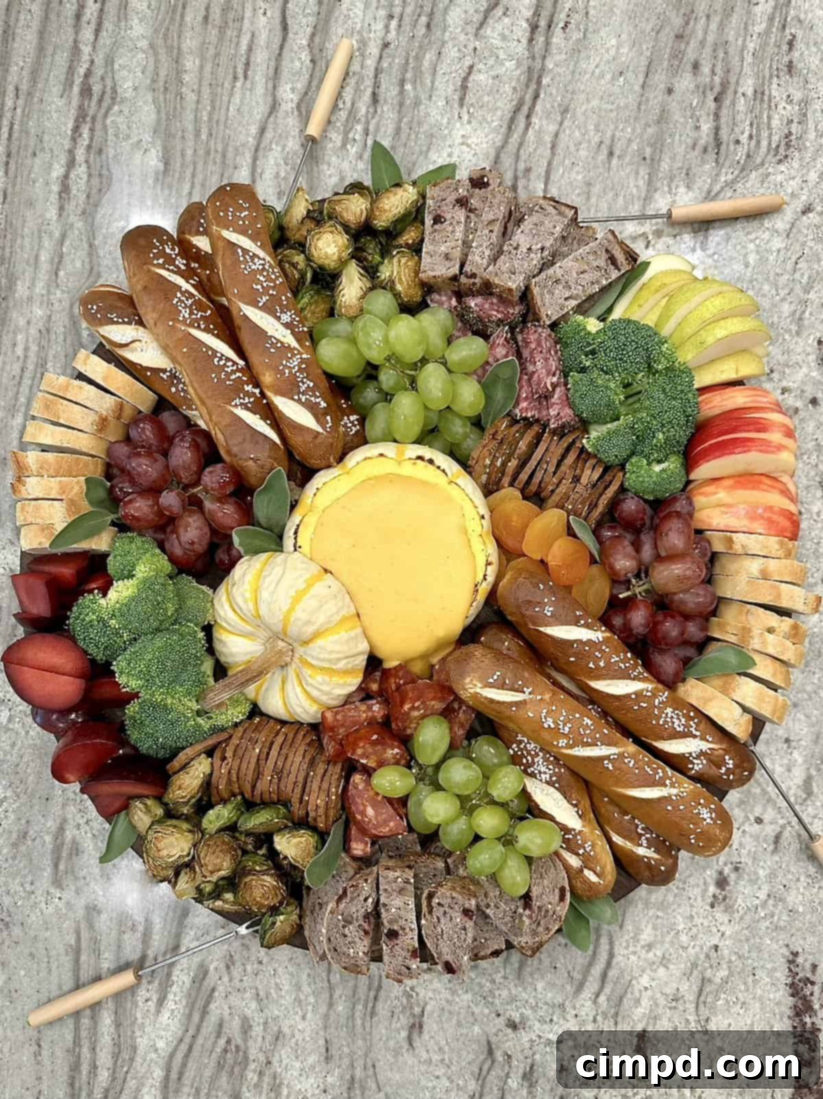 A beautifully arranged Fall Fondue Board by The BakerMama, featuring a baked pumpkin bowl filled with cheese fondue surrounded by various seasonal dippers.