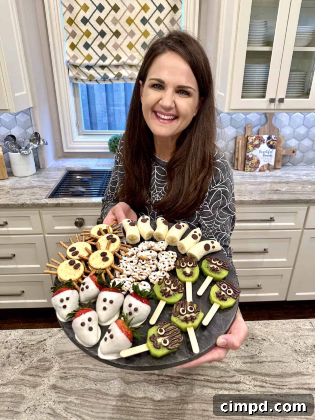 5 Spooktacularly Cute Halloween Goodies 3 A vibrant display of five different spooky cute Halloween treats: Banana Ghosts, Strawberry Ghosts, Frankenstein Kiwi Pops, Peanut Butter Cracker Spiders, and Pretzel Mummies, arranged artfully for a festive presentation.