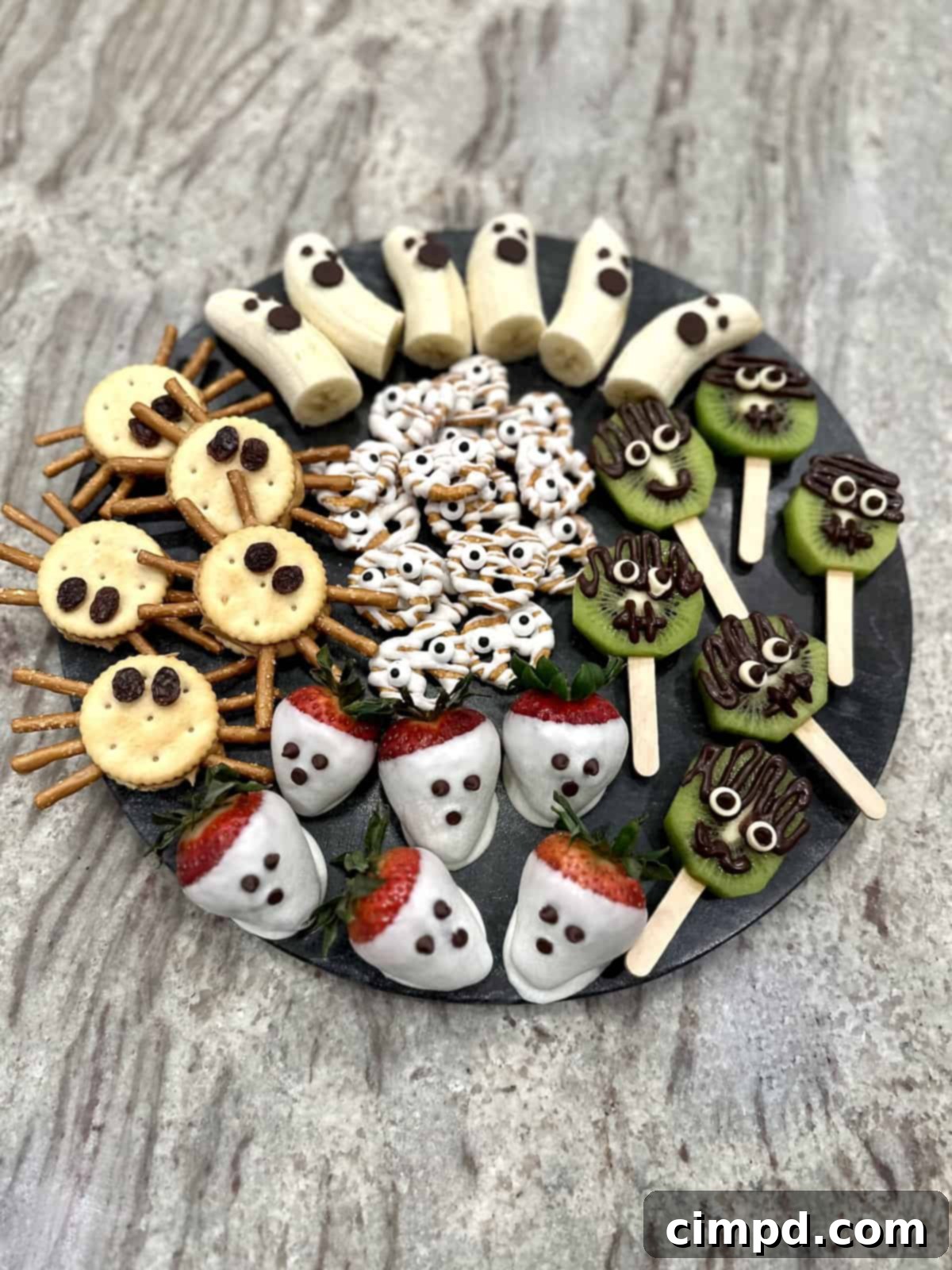 5 Spooktacularly Cute Halloween Goodies 4 A close-up of a variety of Halloween treats including Banana Ghosts, Strawberry Ghosts, and Frankenstein Kiwi Pops, showcasing their cute and spooky details.