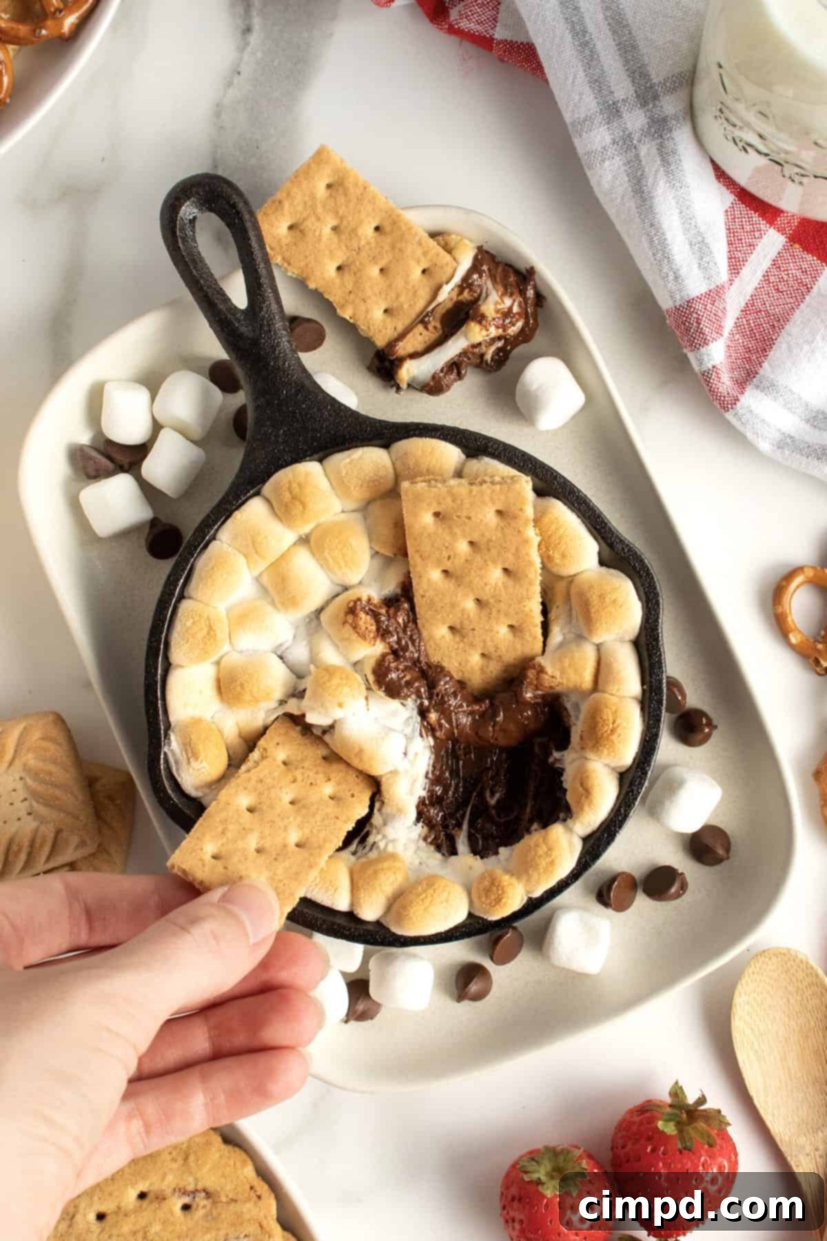 Freshly baked Skillet S'mores Dip, hot out of the oven, with dippers arranged around it.