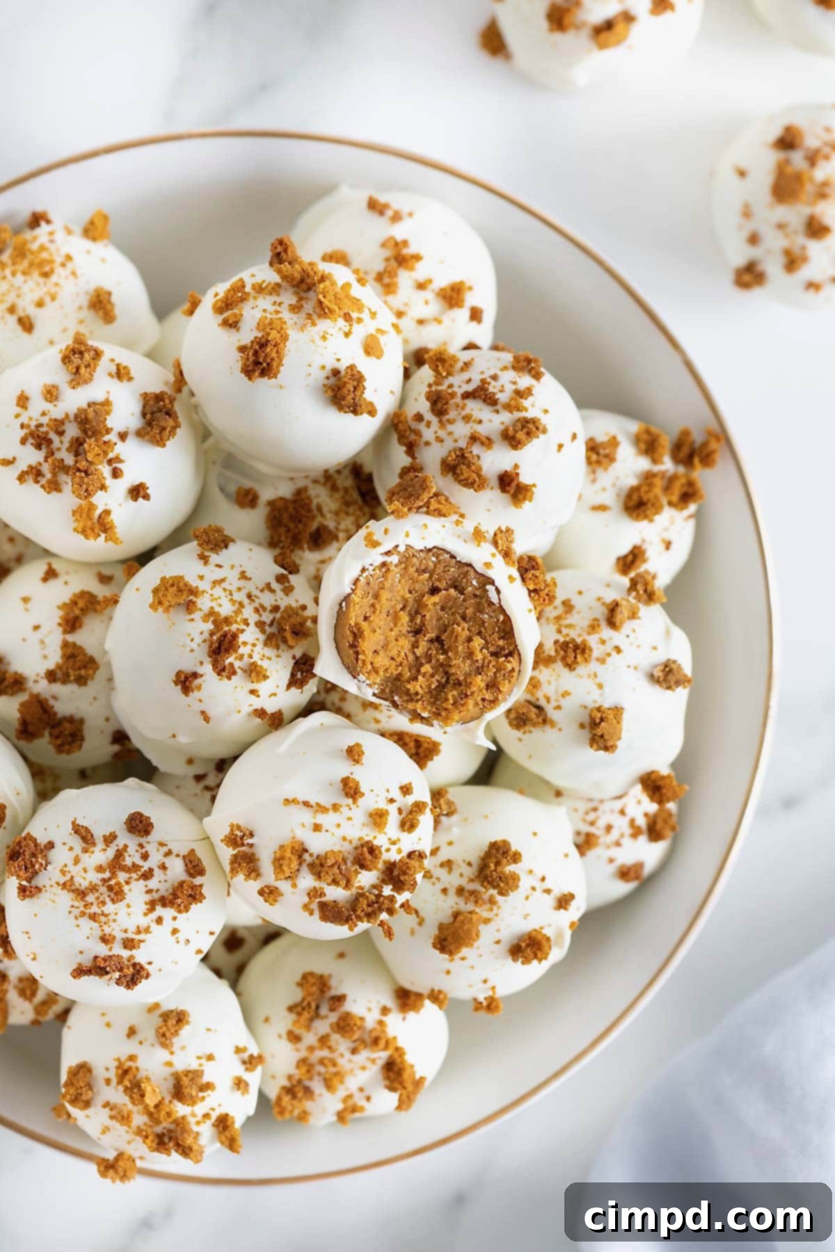 A large white gold-rimmed serving dish filled with pumpkin spice cake balls, inviting autumn treats.