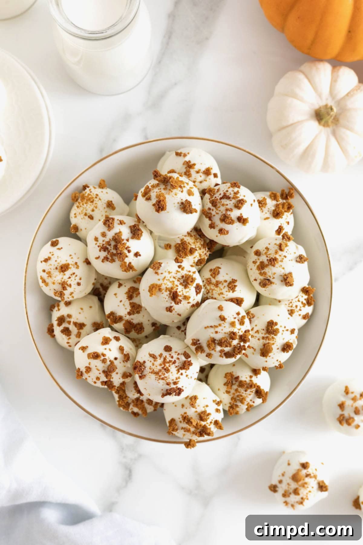 A large white gold-rimmed serving dish showcasing an array of perfectly formed pumpkin spice cake balls, ready for a fall celebration.