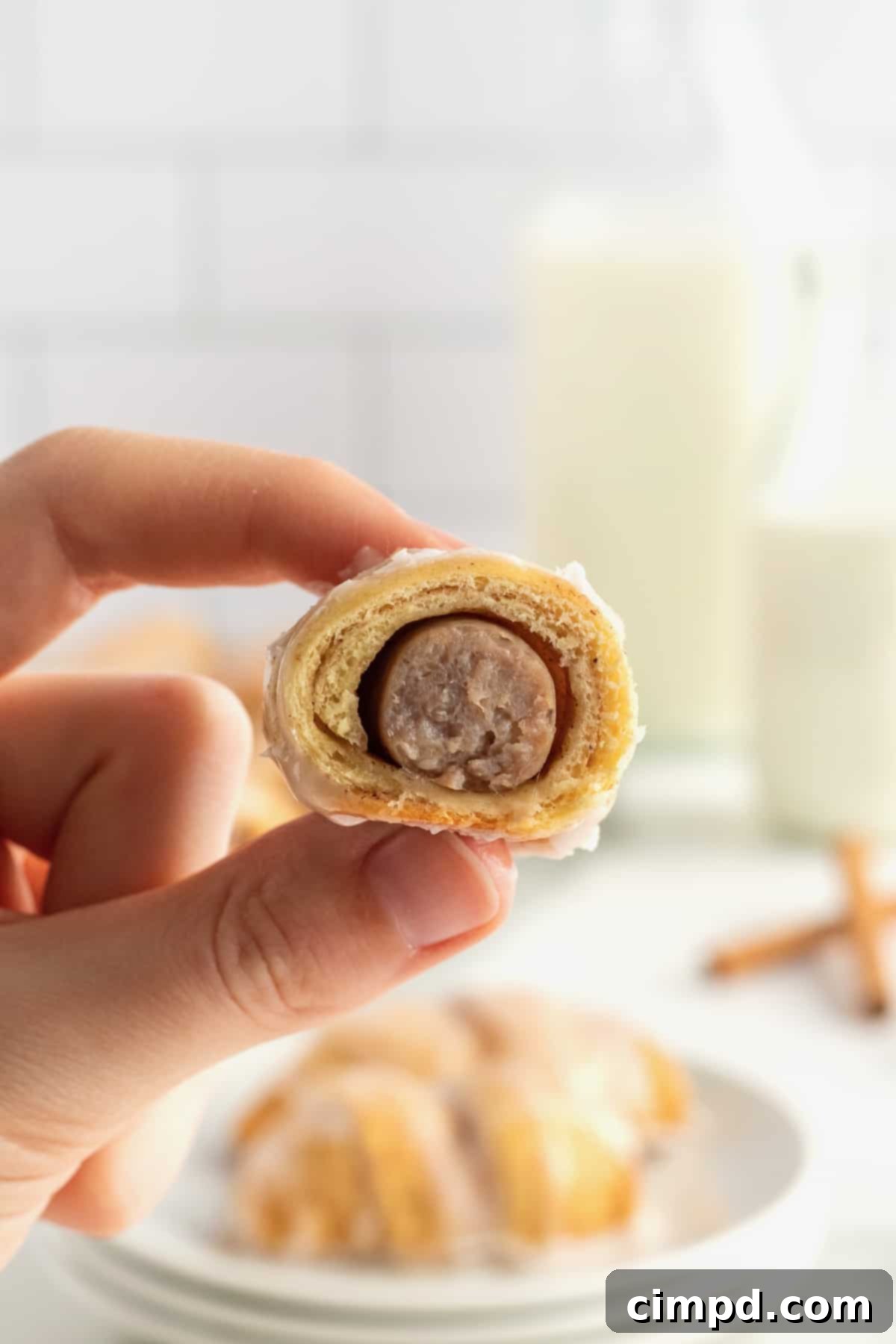 Cinnamon Glazed Sausage Rolls 3 A plate of freshly baked Cinnamon Roll Pigs in a Blanket, glistening with sweet glaze.