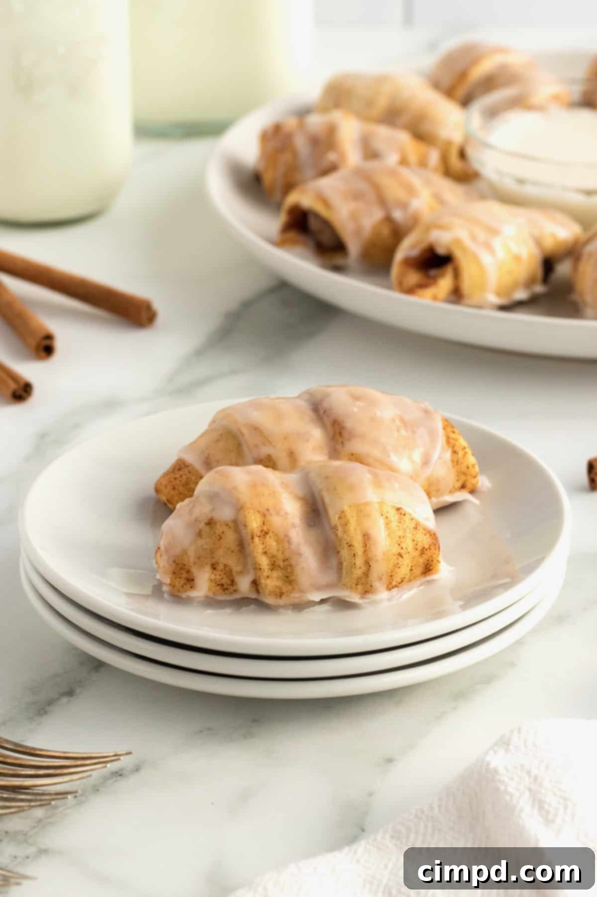 A plate full of Cinnamon Roll Pigs in a Blanket, some with icing.