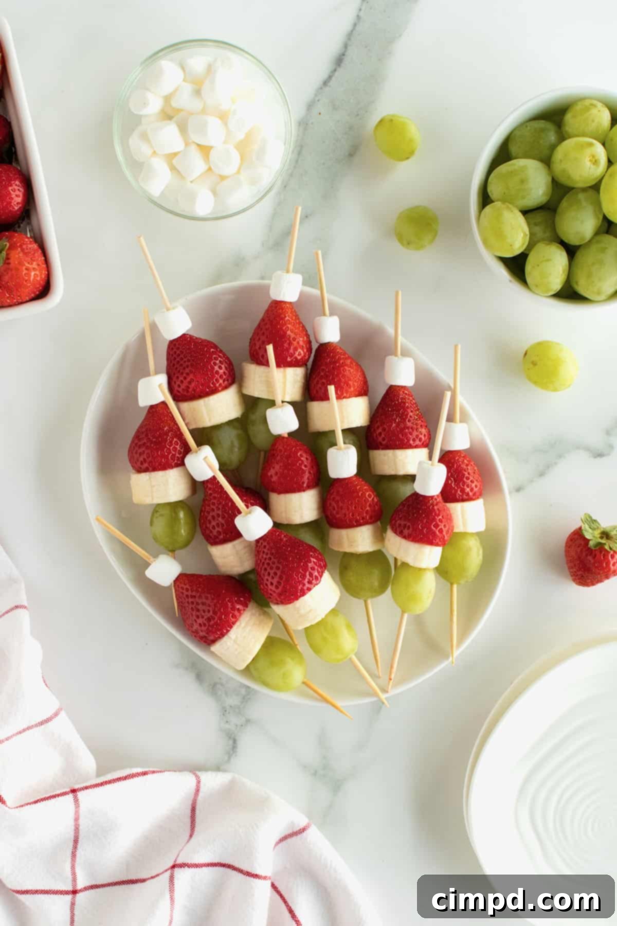 Festive Grinch Fruit Skewers featuring red strawberries, green grapes, and white marshmallows, perfect for holiday parties.
