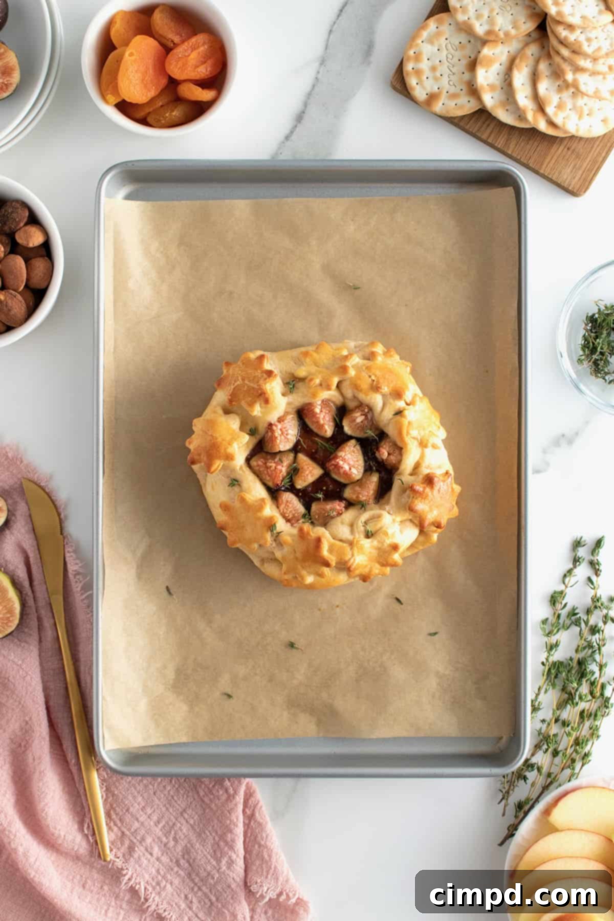 Freshly baked brie with fig jam, golden brown and glistening, resting on a wooden serving board.