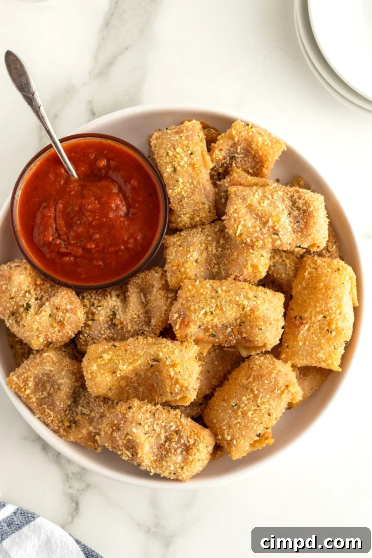 Golden-brown pepperoni pizza pocket bites arranged on a plate with dipping sauce.