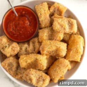 A plate full of golden-brown pepperoni pizza pocket bites with a dipping sauce.