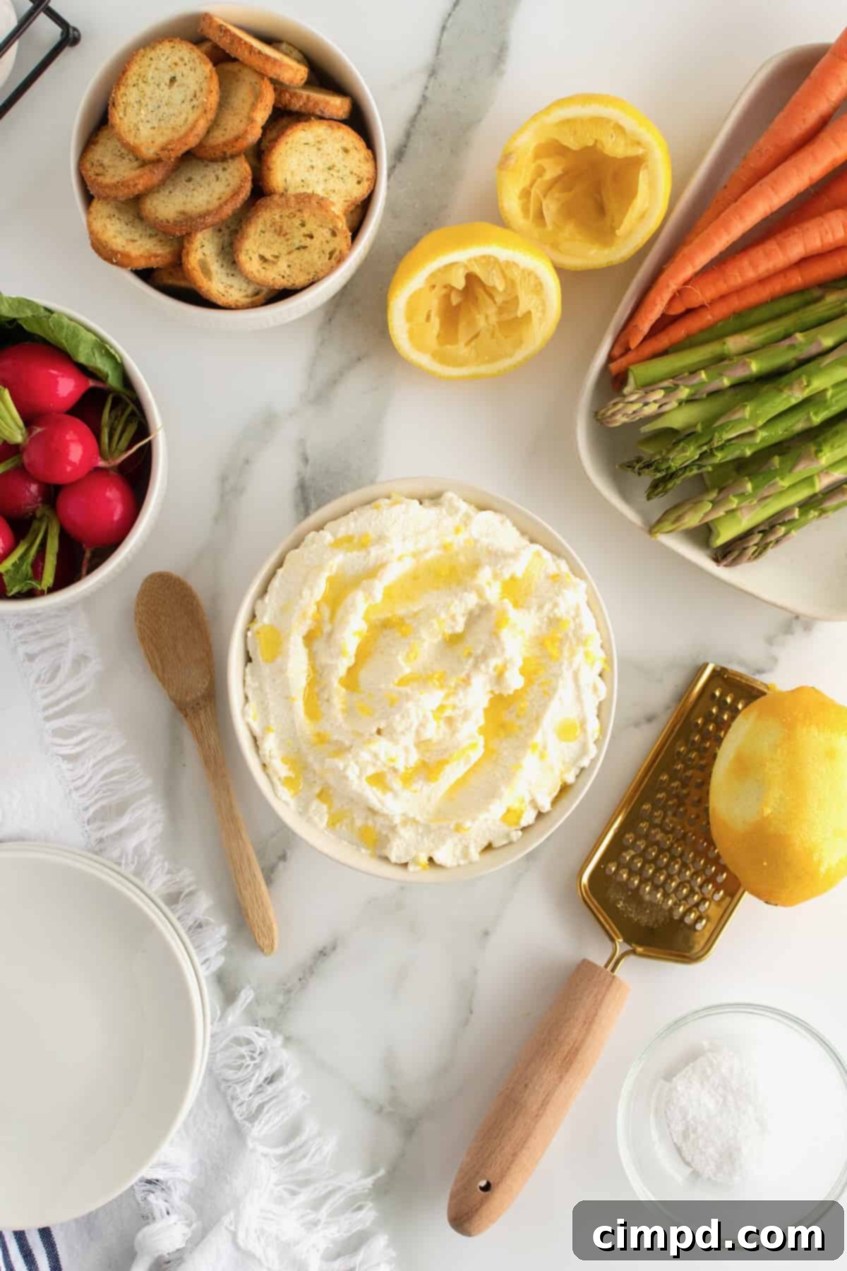 Finished whipped ricotta spread on a serving platter, drizzled with olive oil and garnished with lemon zest.