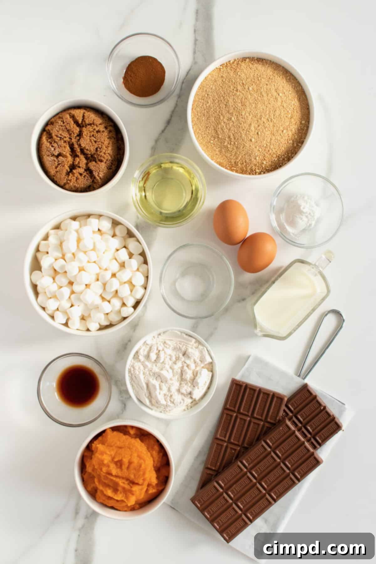 All the dry ingredients for the Pumpkin S'mores Snack Cake laid out in bowls on a wooden surface, ready for mixing.
