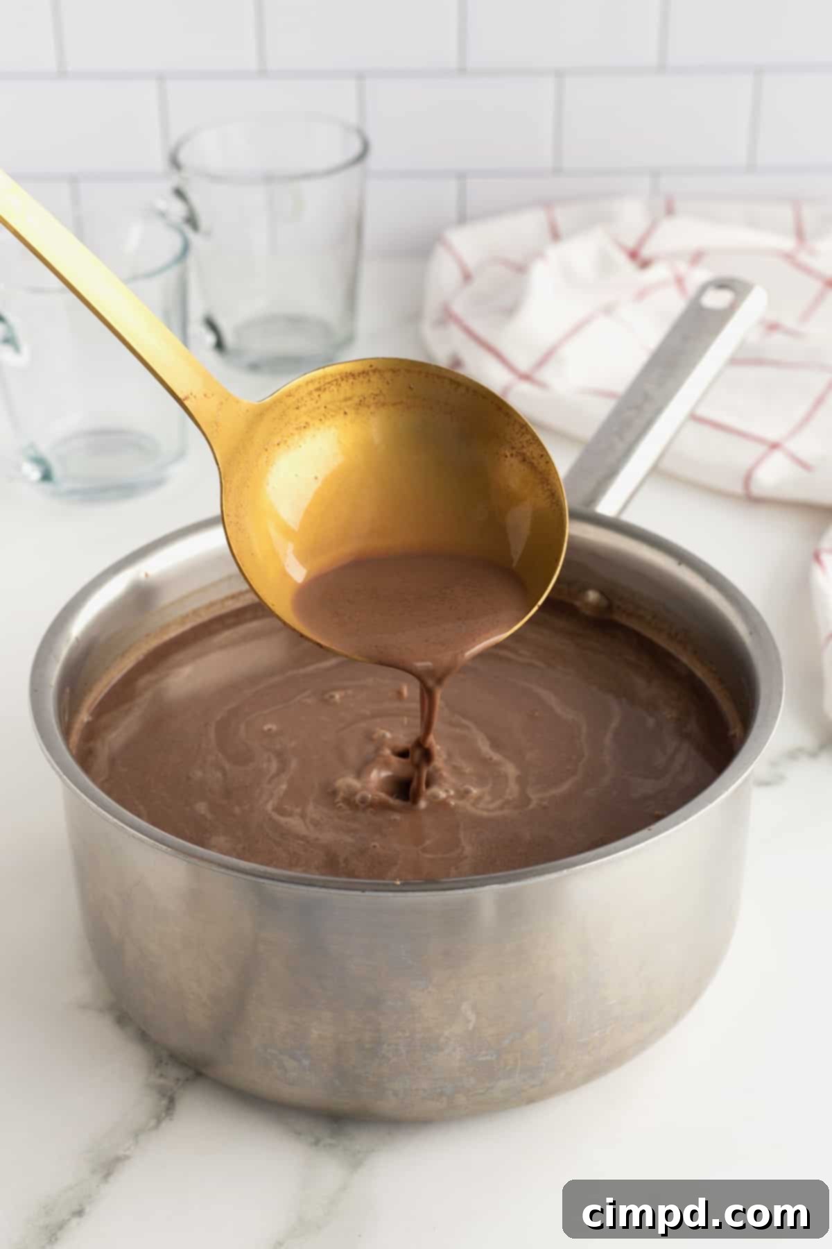 A warm mug of Homemade Hot Chocolate topped with whipped cream and chocolate syrup, ready to be enjoyed.