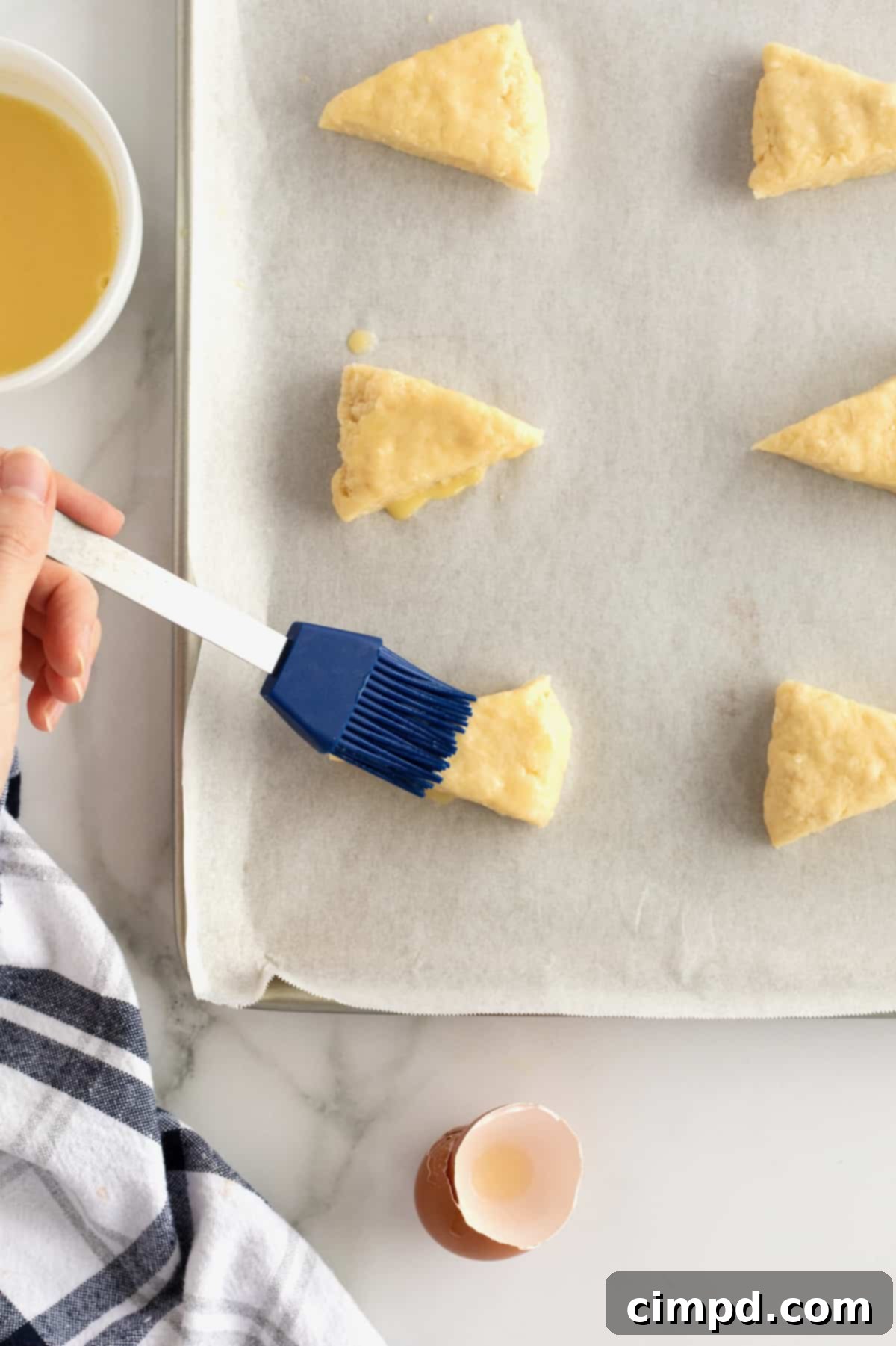 Close-up of pastries with a golden, glossy egg wash applied, ready for baking.