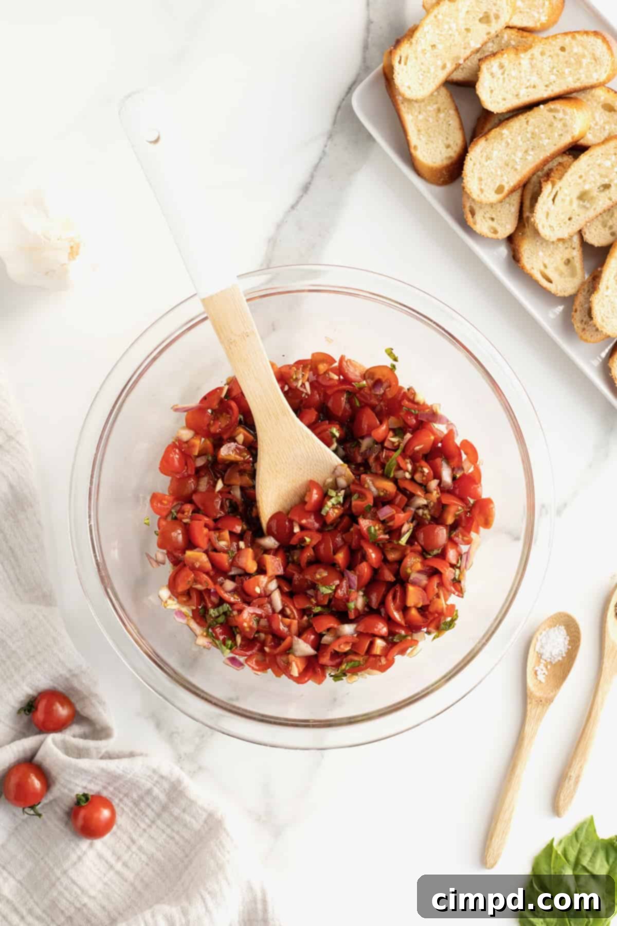 Classic Tomato Bruschetta mixture marinating in a bowl, covered with plastic wrap.
