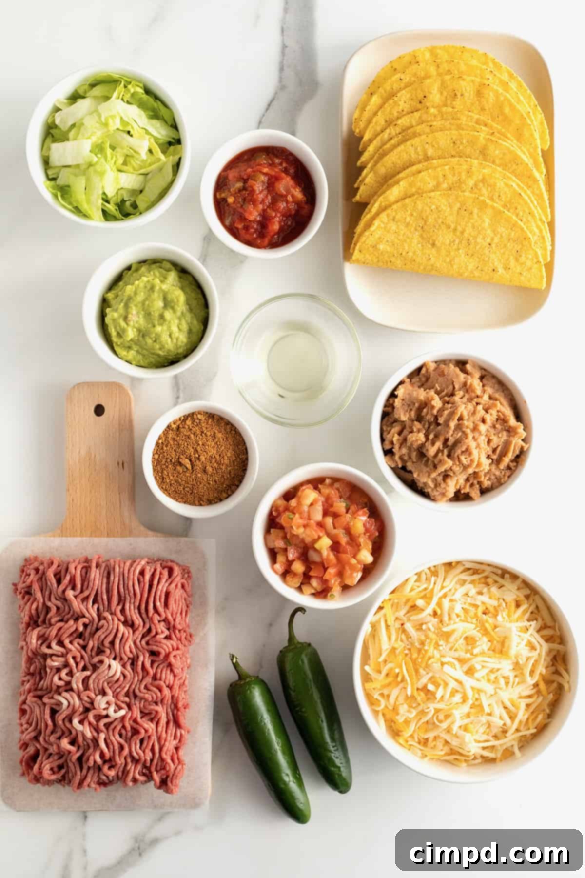 Ingredients for Beef and Bean Baked Tacos, neatly arranged on a counter, including ground beef, beans, shells, and toppings, by The BakerMama